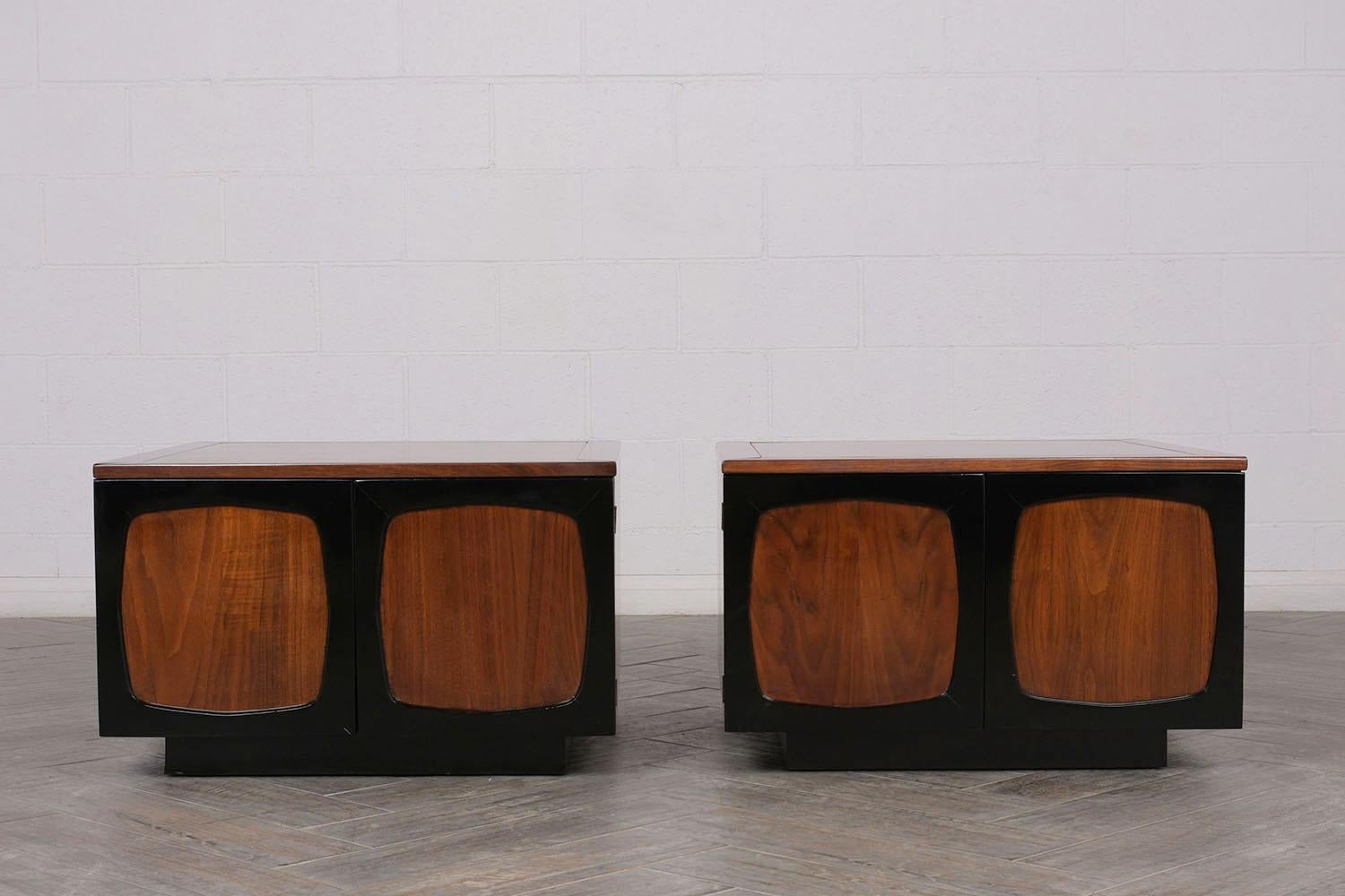 This Pair of 1970's Mid-Century Modern-style Cube Nightstands have been fully restored and have been newly stained in a walnut & black color combination with a lacquered finish. The pair of side tables feature carved wood details, two doors with