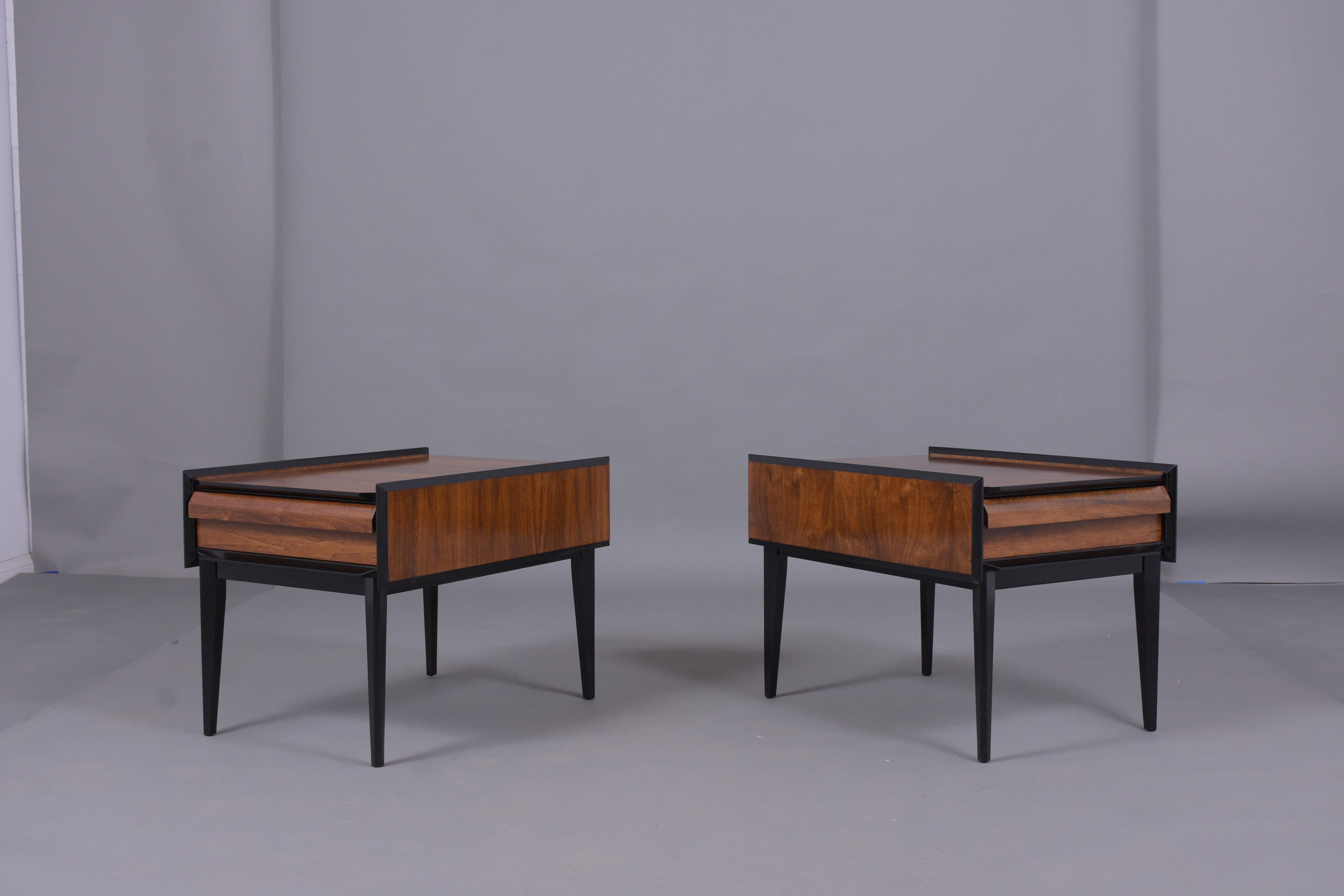 This pair of mid-century modern side tables are made out of walnut wood and have been professionally restored by our team of craftsmen in-house. The pair of bedside tables come with a new finish in a provincial and ebonized color combination with