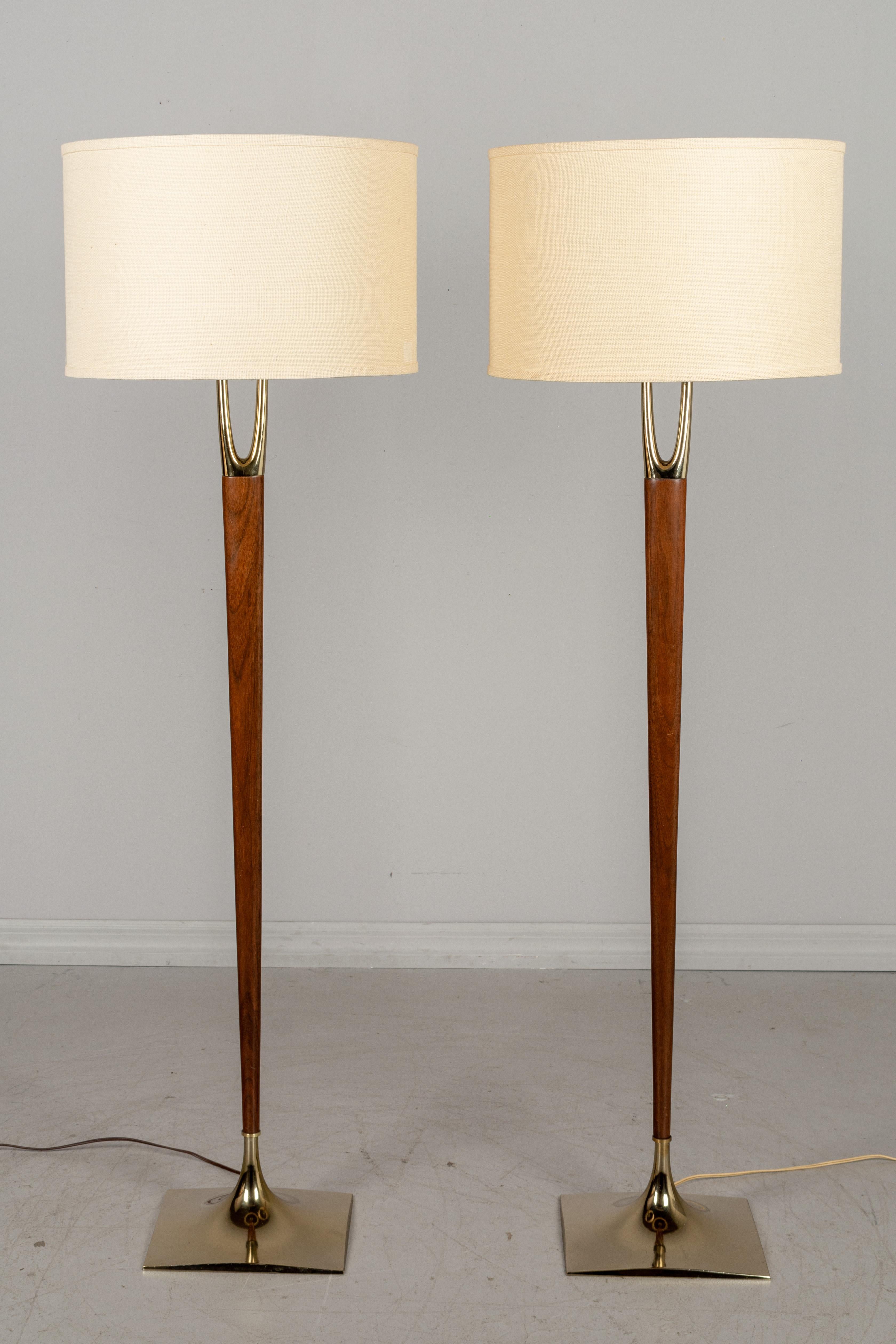 A rare pair of iconic, sought after Mid-Century Modern floor lamps designed by Gerald Thurston and made by the Laurel Lamp Company. Solid walnut center post with brass-plated wishbone shaped prong at top and a brass-plated base. Original wide