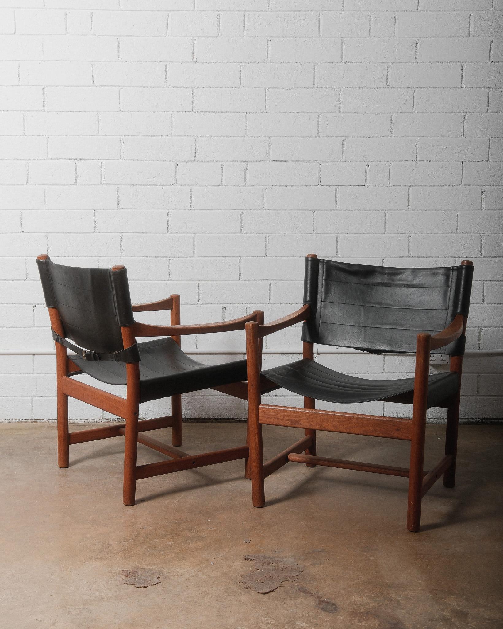 Cette paire de fauteuils en bois et cuir de style milieu de siècle des années 1970, fabriqués en bois massif teinté et dotés de cuir cannelé durable pour le dossier et l'assise, est un bel ajout à votre intérieur. Les chaises sont méticuleusement
