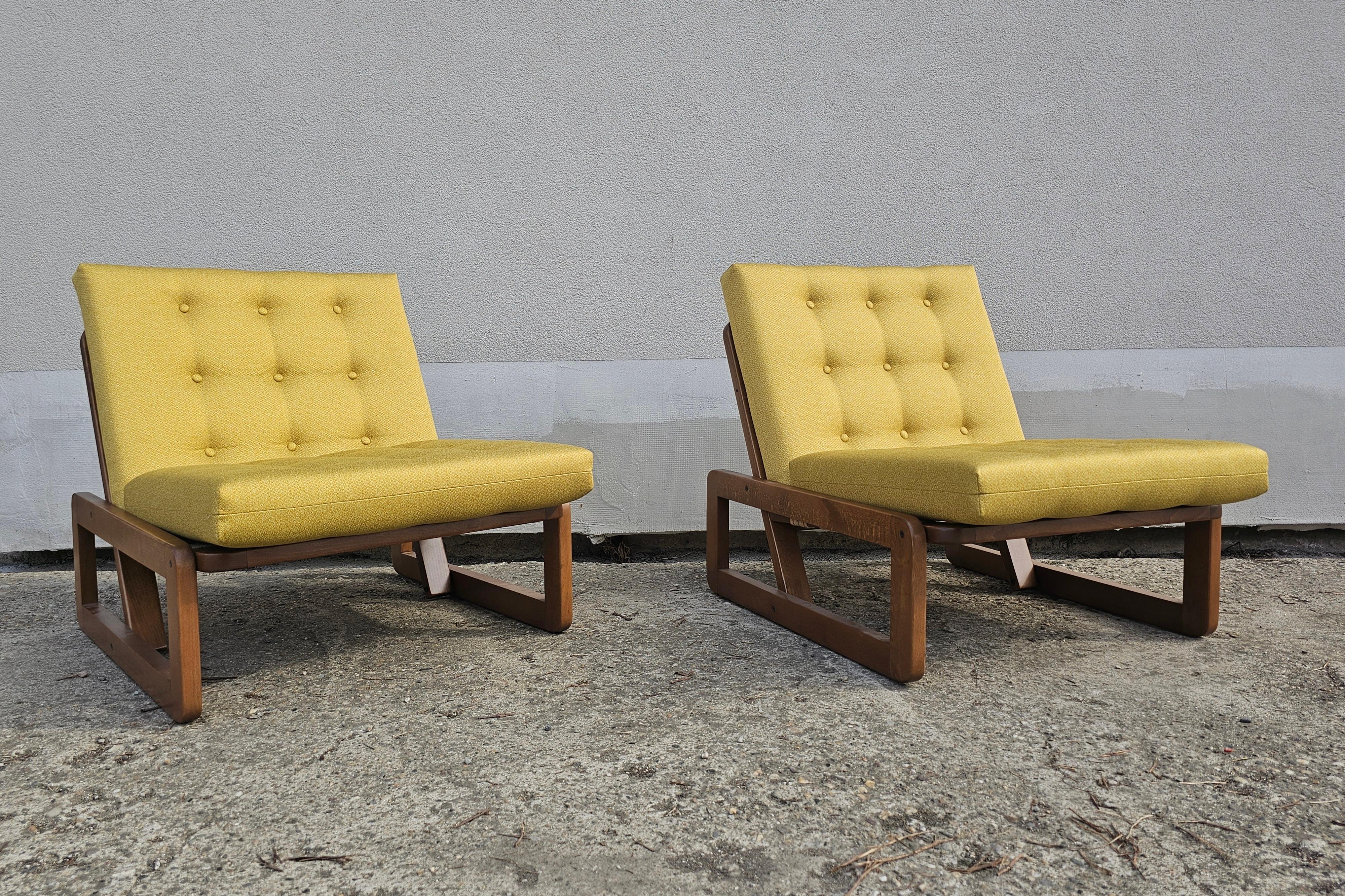 In this listing you will find a pair of Mid Century Modern lounge chairs designed by Branko Ursic for Stol Kamnik. The chairs feature geometric shape and wooden construction made of beech. The cushions are done in mustard yellow fabric. Made in