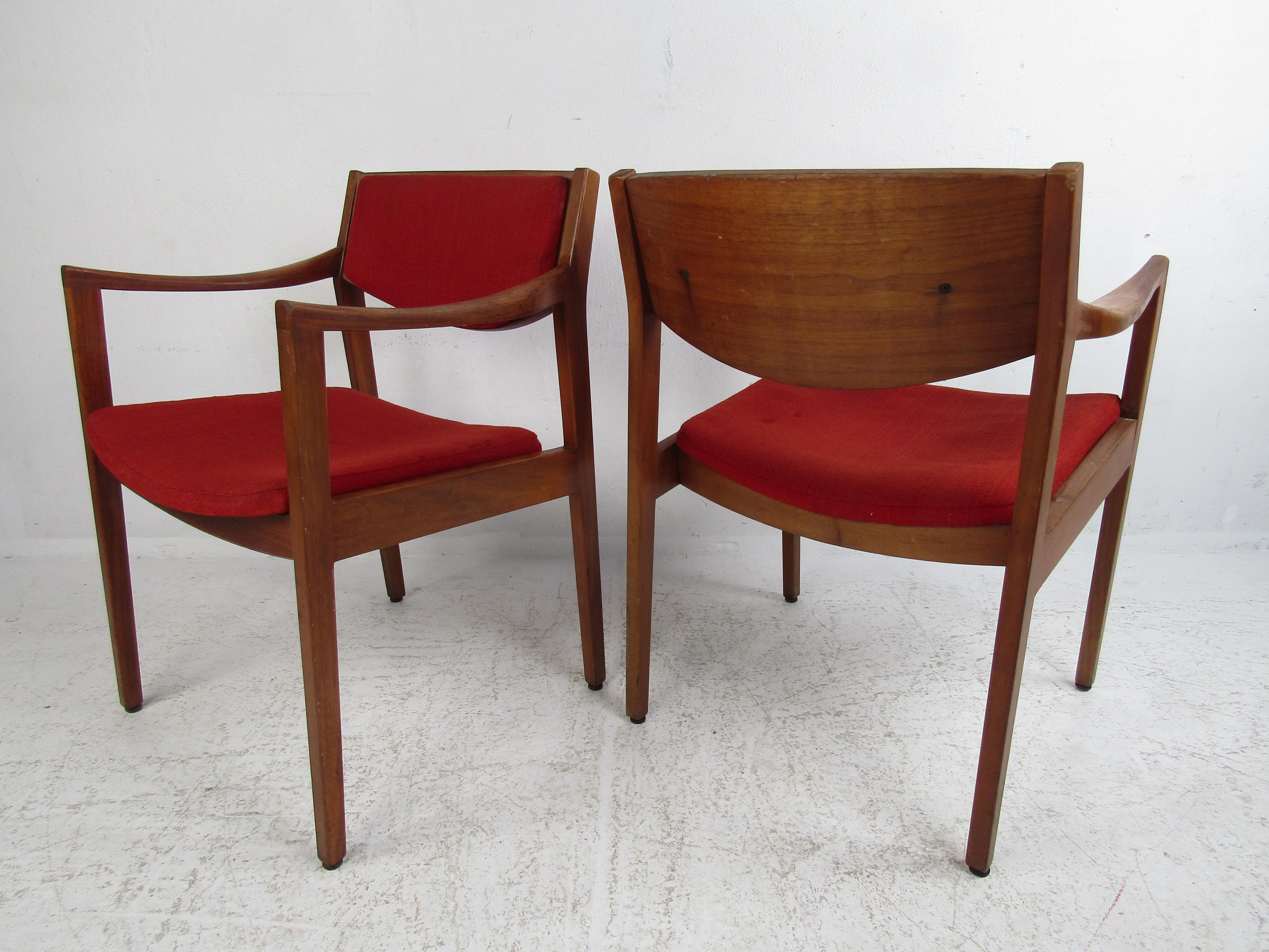 Dieses atemberaubende Paar moderner Sessel im Vintage-Stil hat ein Gestell aus dunklem Walnussholz mit geschwungenen Armlehnen und gepolsterten Rückenlehnen. Ein wunderbares Design, das für Komfort sorgt, ohne auf Stil zu verzichten. Dieses Paar