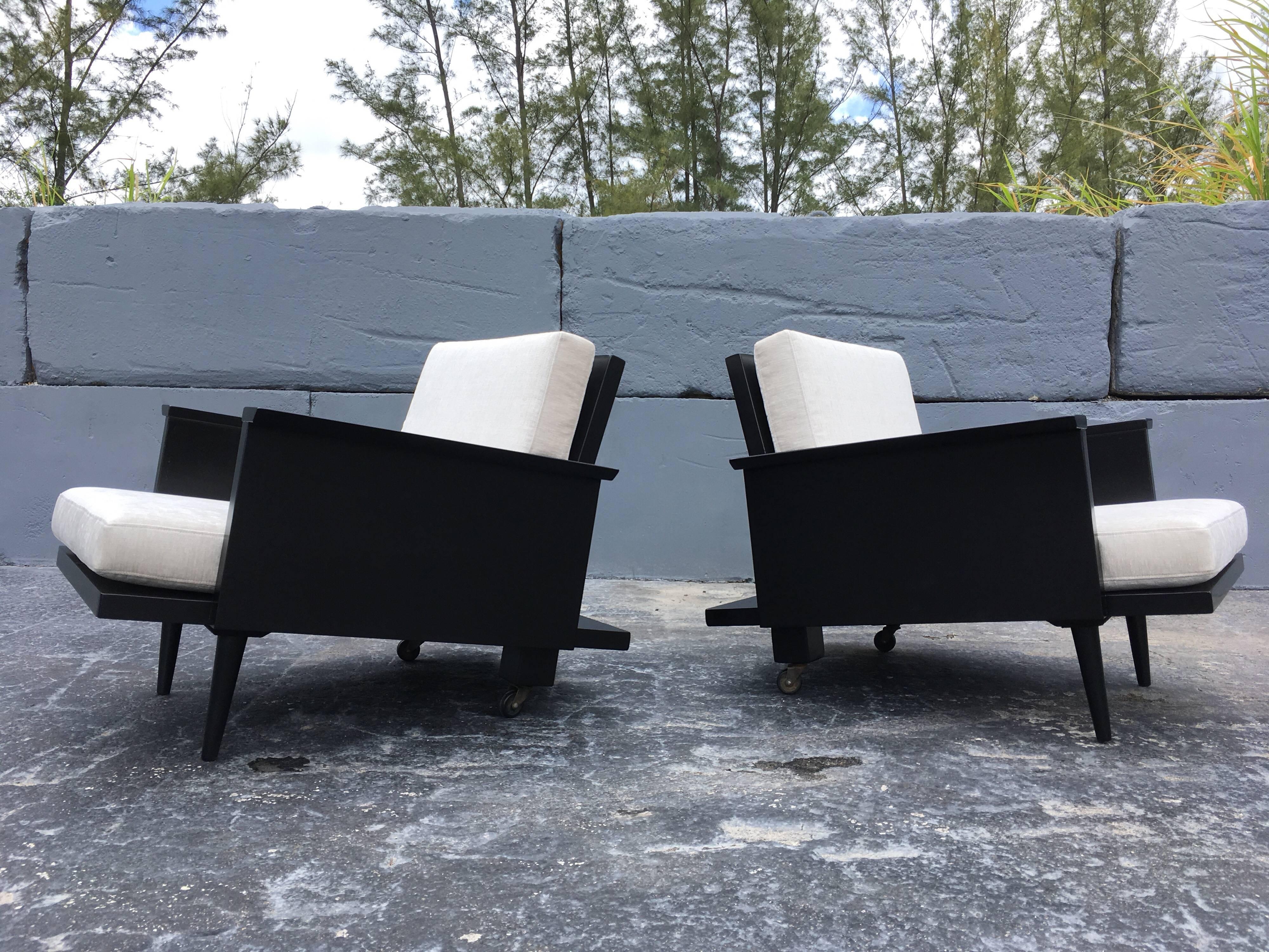 Very interesting pair of 1950s lounge chairs by Modernage. Black painted wood frames with tapered front legs and casters at the back.