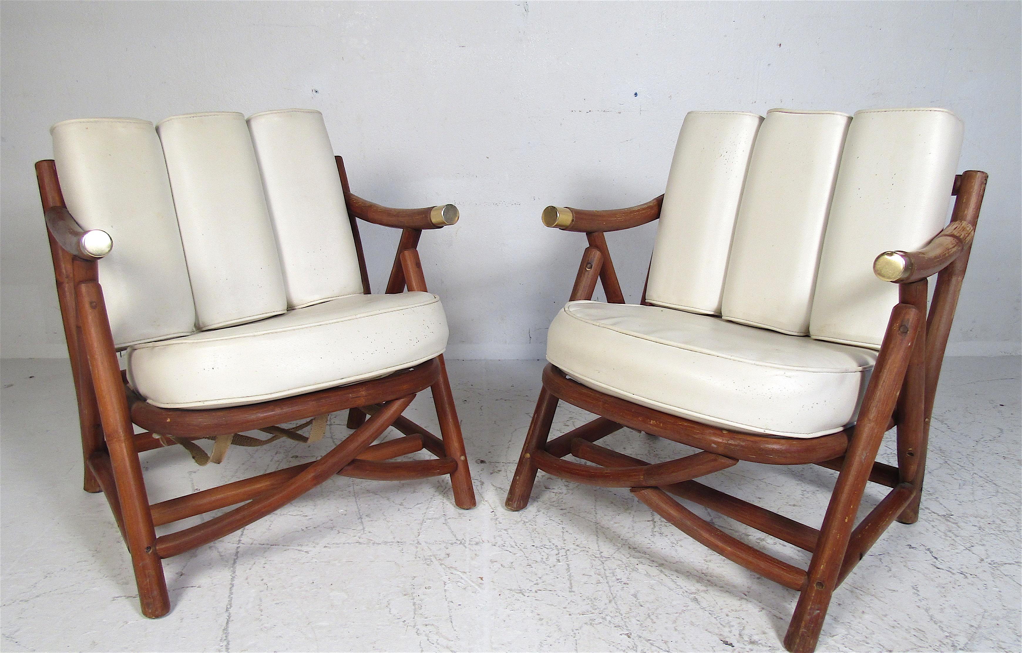 This unusual pair of vintage modern lounge chairs feature a cylindrical wood frame and two thick padded cushions. This sturdy and stylish pair ensures maximum comfort. The slatted backrest and brass capped armrests show true quality craftsmanship.