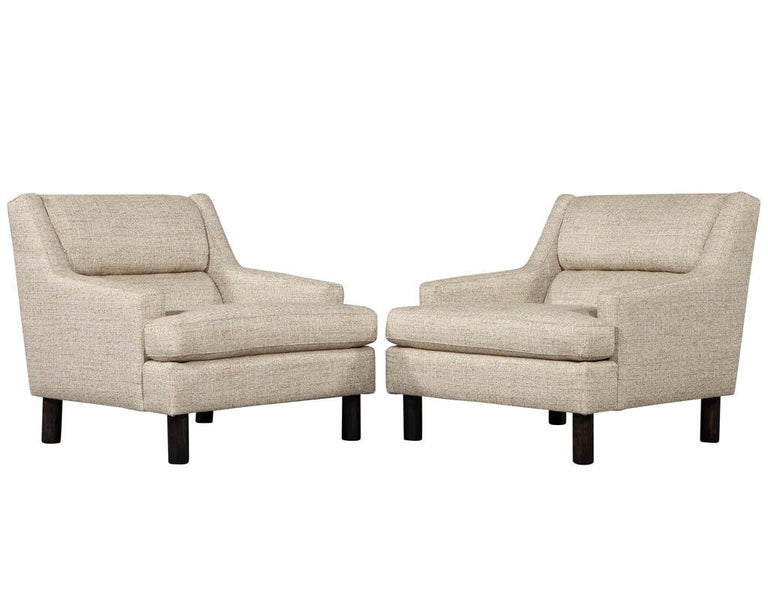 Pair of Mid-Century Modern lounge chairs. Timeless Mid-Century Modern design with comfortable large upholstered features. Upholstered in a textured sandy beige designer Linen with cylindrical walnut feet.

Price includes complimentary scheduled