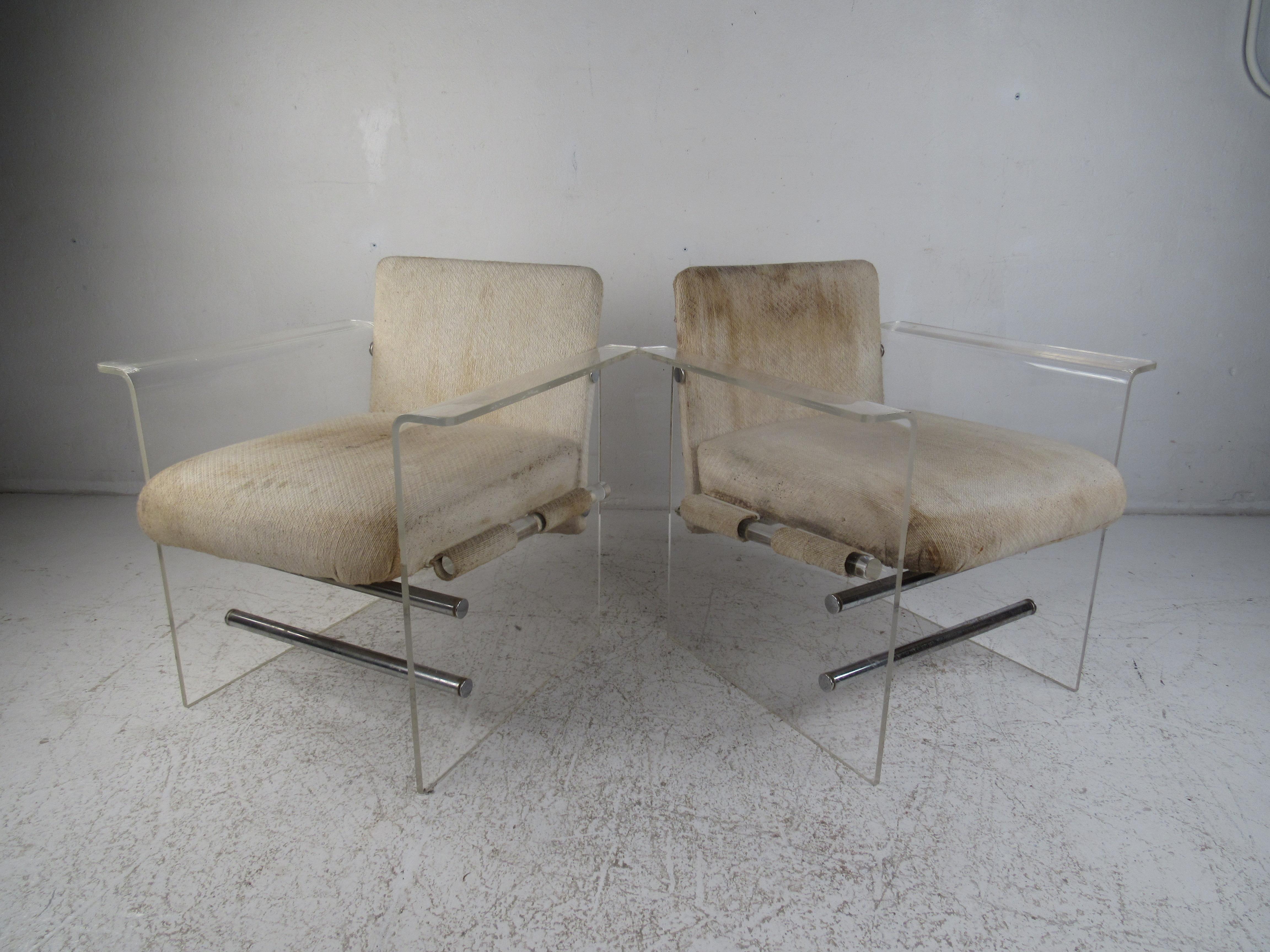 An unusual pair of vintage modern lounge chairs that feature Lucite sides connected by chrome cylindrical stretchers. The sleek design allows for the Lucite sides to function as a base and unique winged arm rests. This Pace style pair of arm chairs