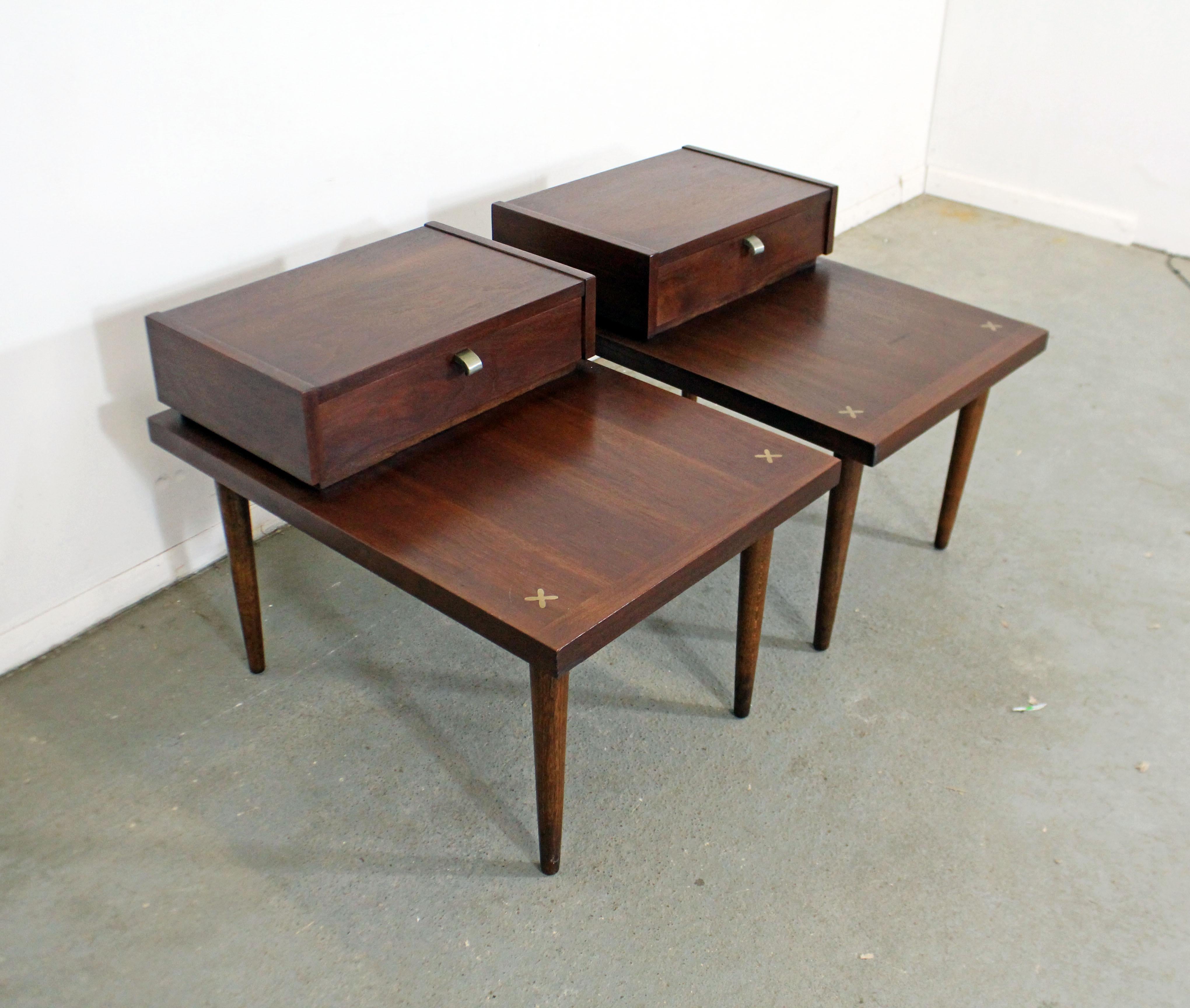 Offered is a pair of walnut end tables designed by Merton L. Gershun for American of Martinsville. Each table has one dove-tailed drawer with a metal pull. Features the iconic X-shaped brushed aluminum inlaid detailing in the tabletops. In good