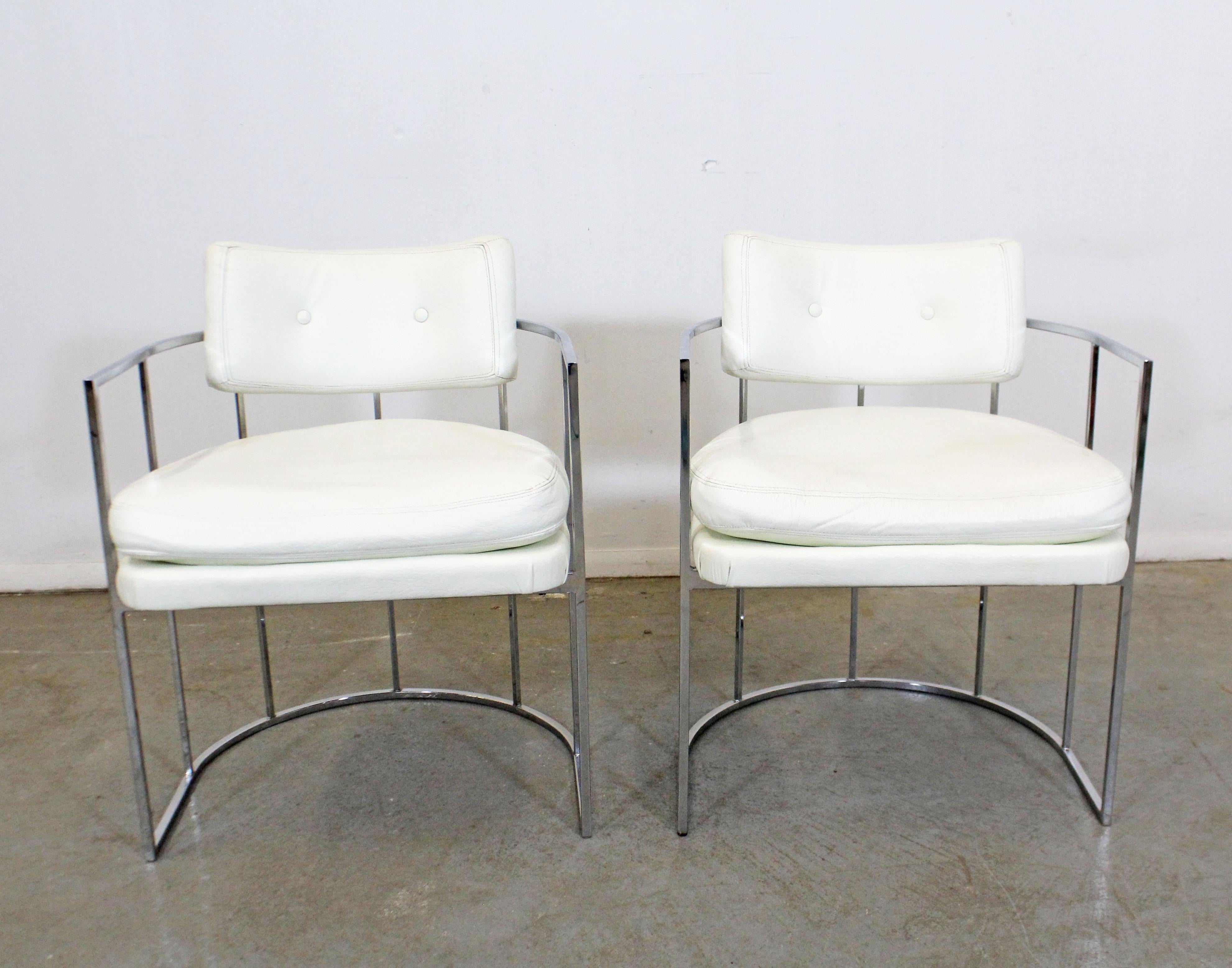 What a find. Offered is a pair of sleek and elegant vintage Mid-Century Modern chrome arm chairs. They were designed by Milo Baughman for Thayer Coggin. These chairs are having chrome bases with rounded backs and white vinyl upholstery. They're in