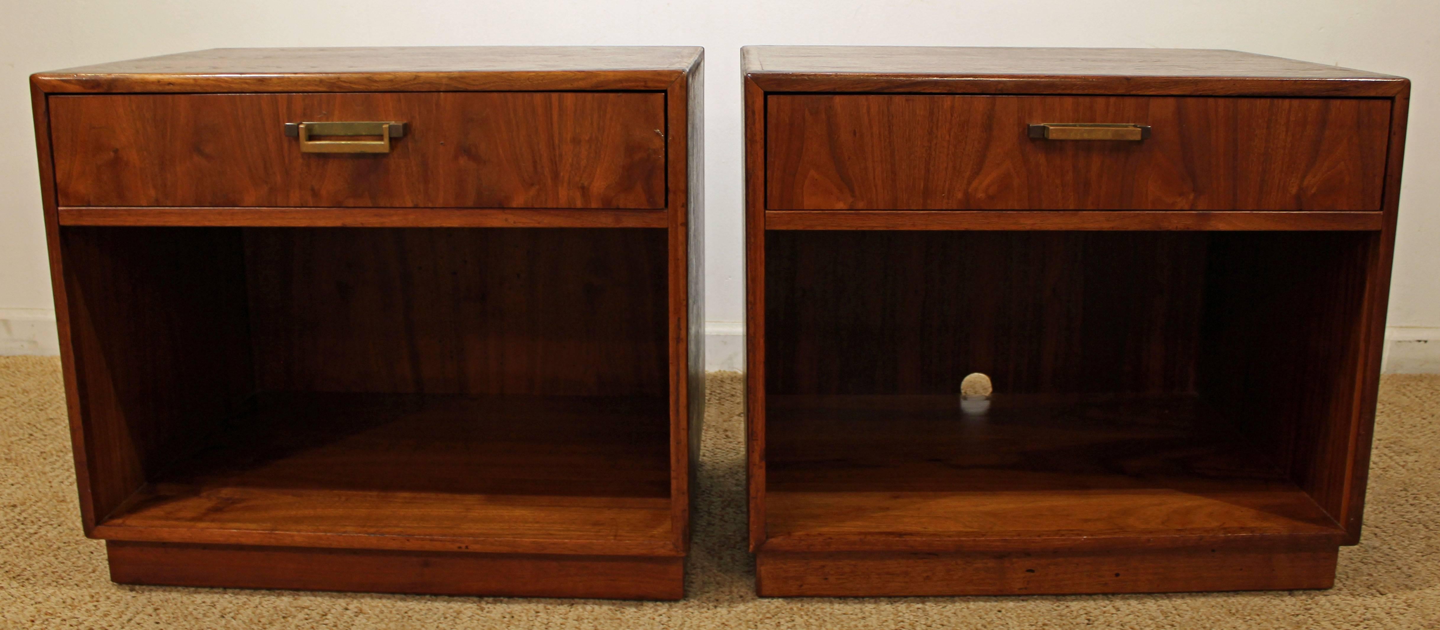 Offered is a pair of Mid-Century Modern nightstands, designed by Milo Baughman for Founders. They are made of walnut with a burl wood-face and brass pulls. Includes one single drawer and storage underneath. They have been