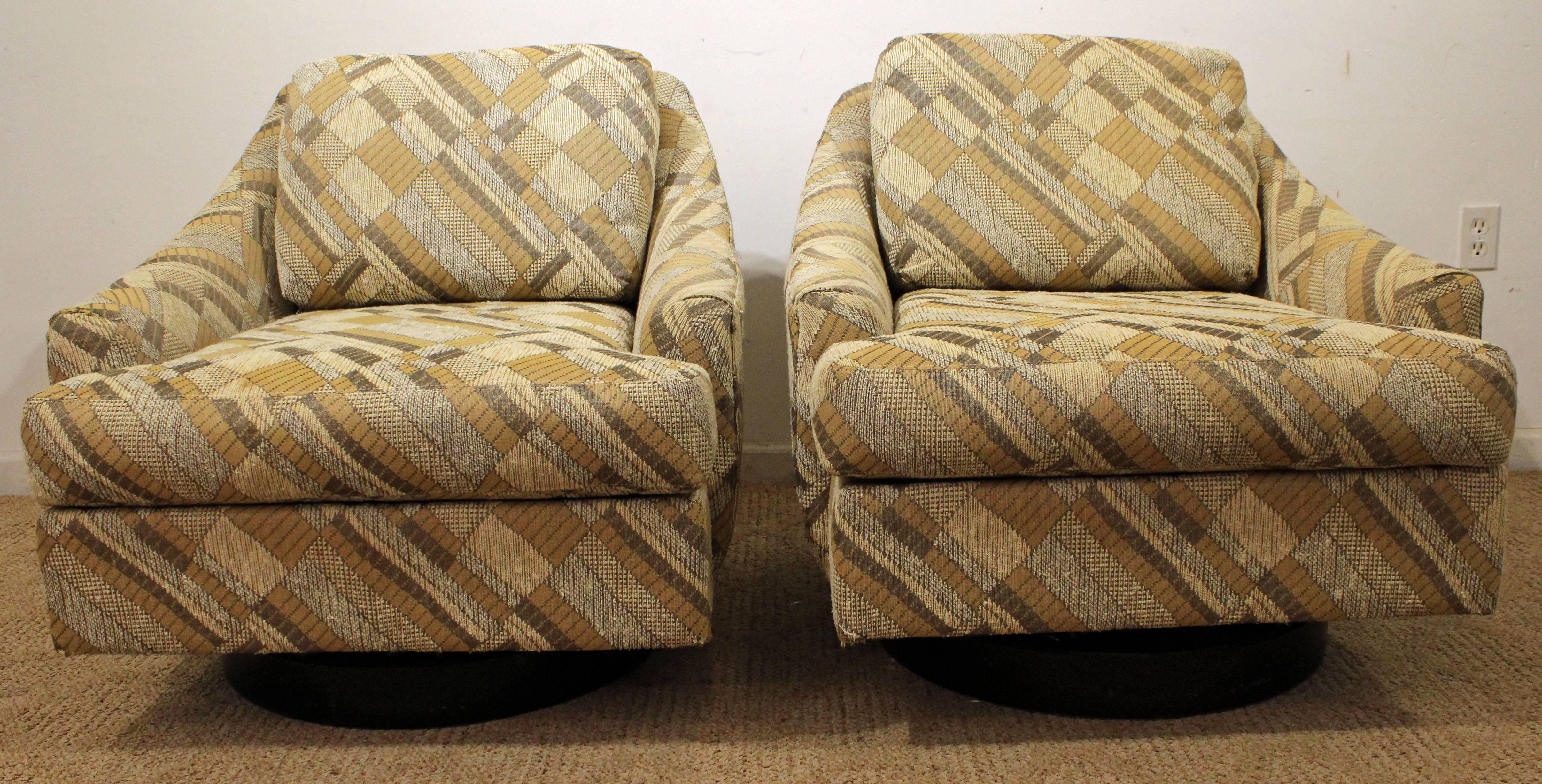 These chairs swivel and feature a walnut base with geometric pattern upholstery.
