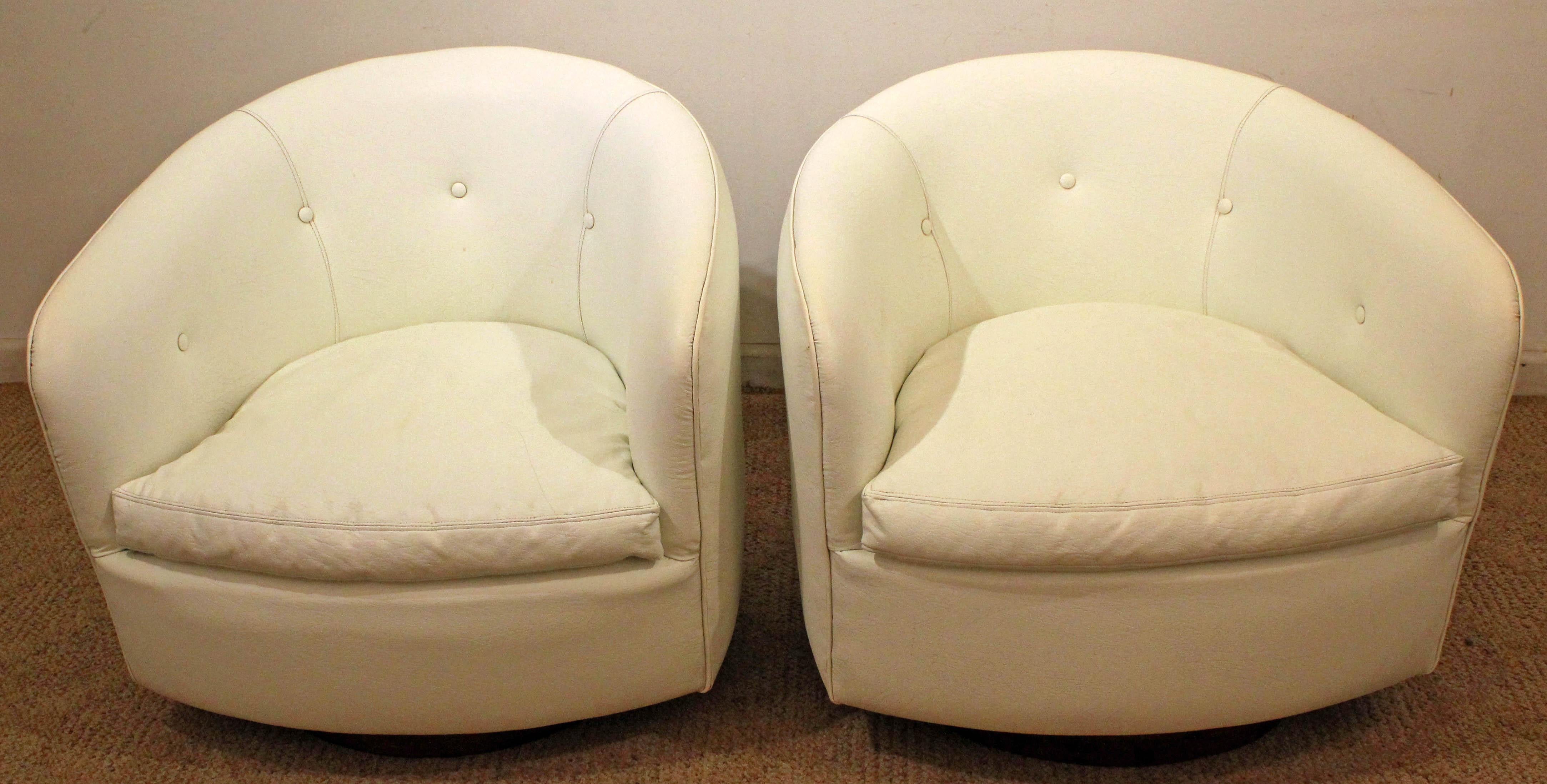 What a find. Offered is a pair of Mid-Century Modern swivel chairs, designed by Milo Baughman for Thayer Coggin. This set has the ability to swivel and tilt with a round walnut base. Features its original white vinyl upholstery. They are signed by