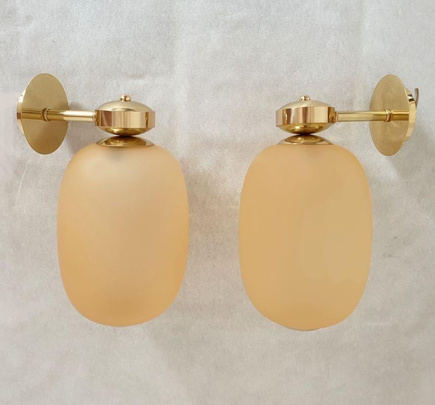Pair of Mid-Century-Modern Murano glass and brass sconces, Barovier & Toso style, Italy, 1980s.
Each sconce has a Murano glass globe, oval shape, in amber color and translucent.
Creates a warm halo of light when lit.
1 Light bulb each.
The