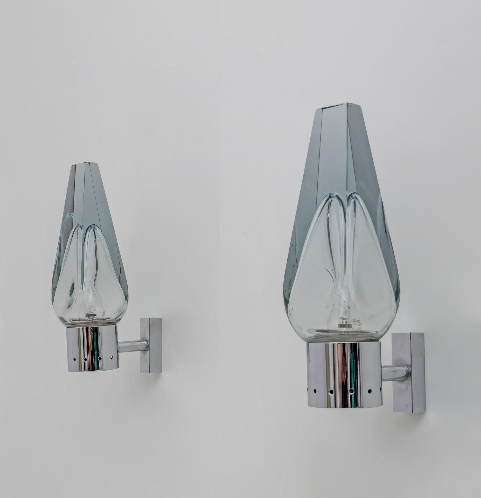 Pair of wall lights by Flavio Poli for Seguso, in chromed brass and Murano glass. Designed and produced in Italy, around the 1960s. Beautiful thick, tapered glass is the centerpiece of these sconces. The glass has a light blue hue and a central