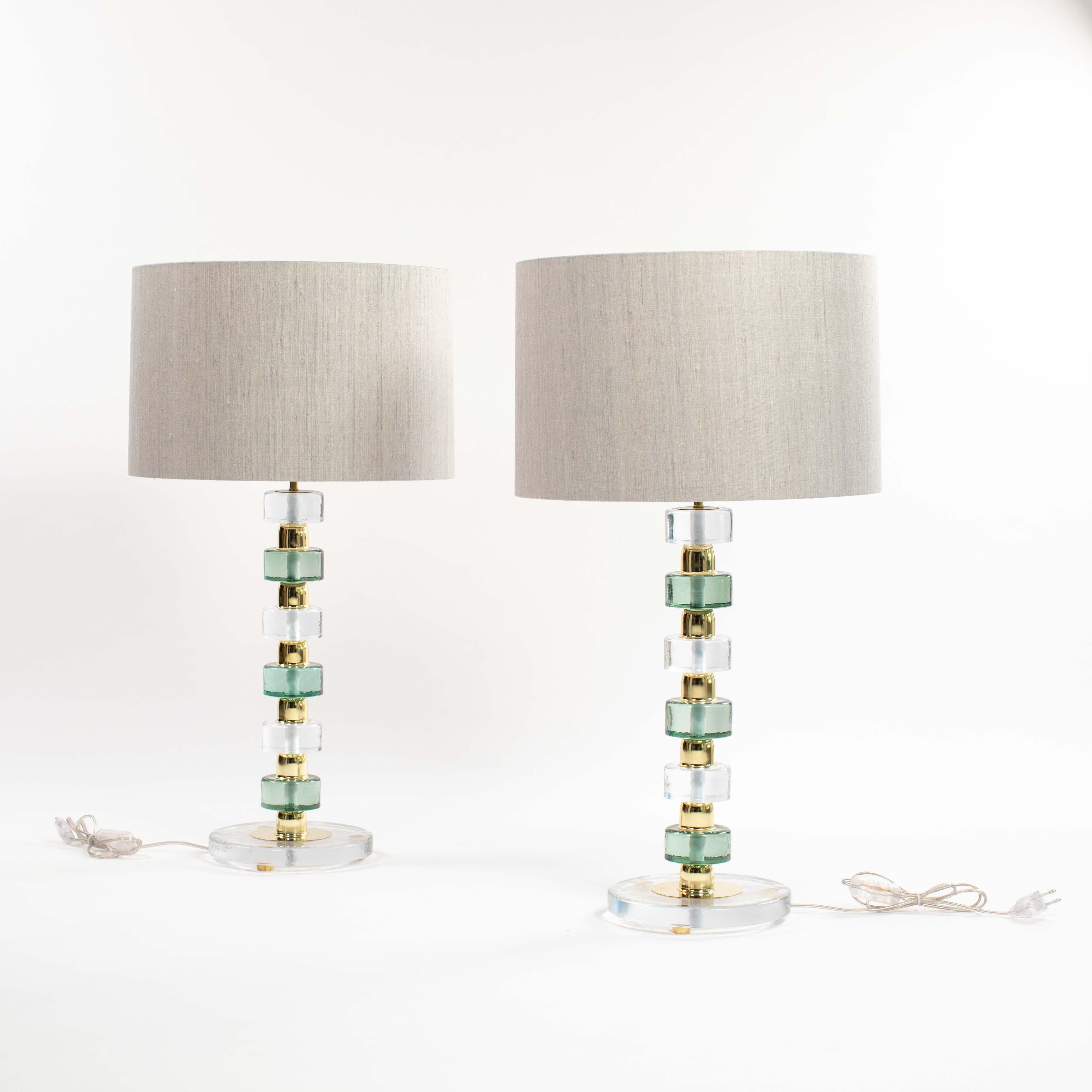 Pair of light-footed Murano glass table lamps with alternating transparent and emerald green glass discs.
A brass spacer with a small lip at the bottom is placed between them.
The base has a diameter of 23cm, the discs 8.0cm, the discs are 4.0cm