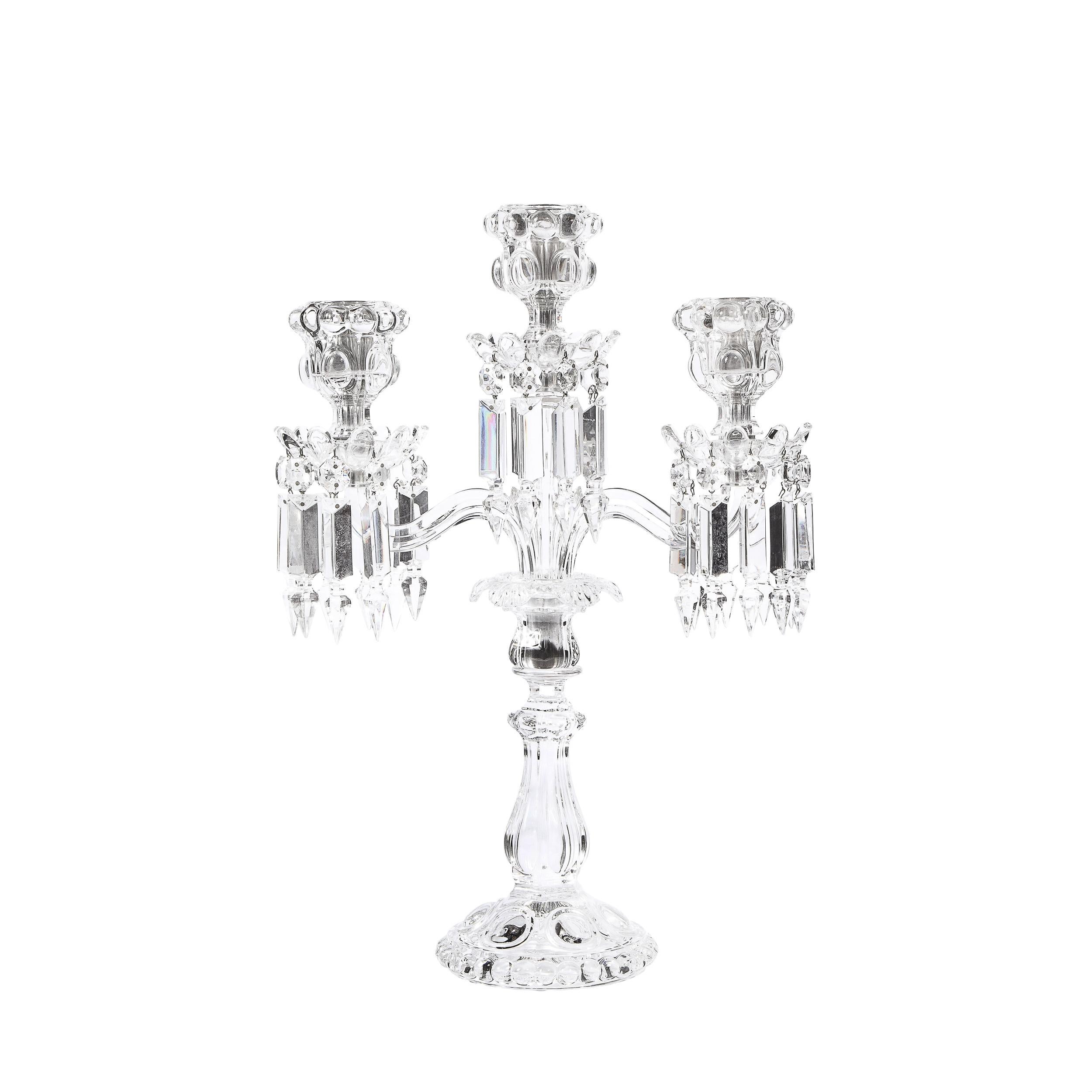 This stunning pair of candelabras were realized by Baccarat- one of the world's premiere makers of luxury glass products since the 18th century- in France circa 1950. Realized in handblown, etched, and beveled translucent crystal, these candelabras
