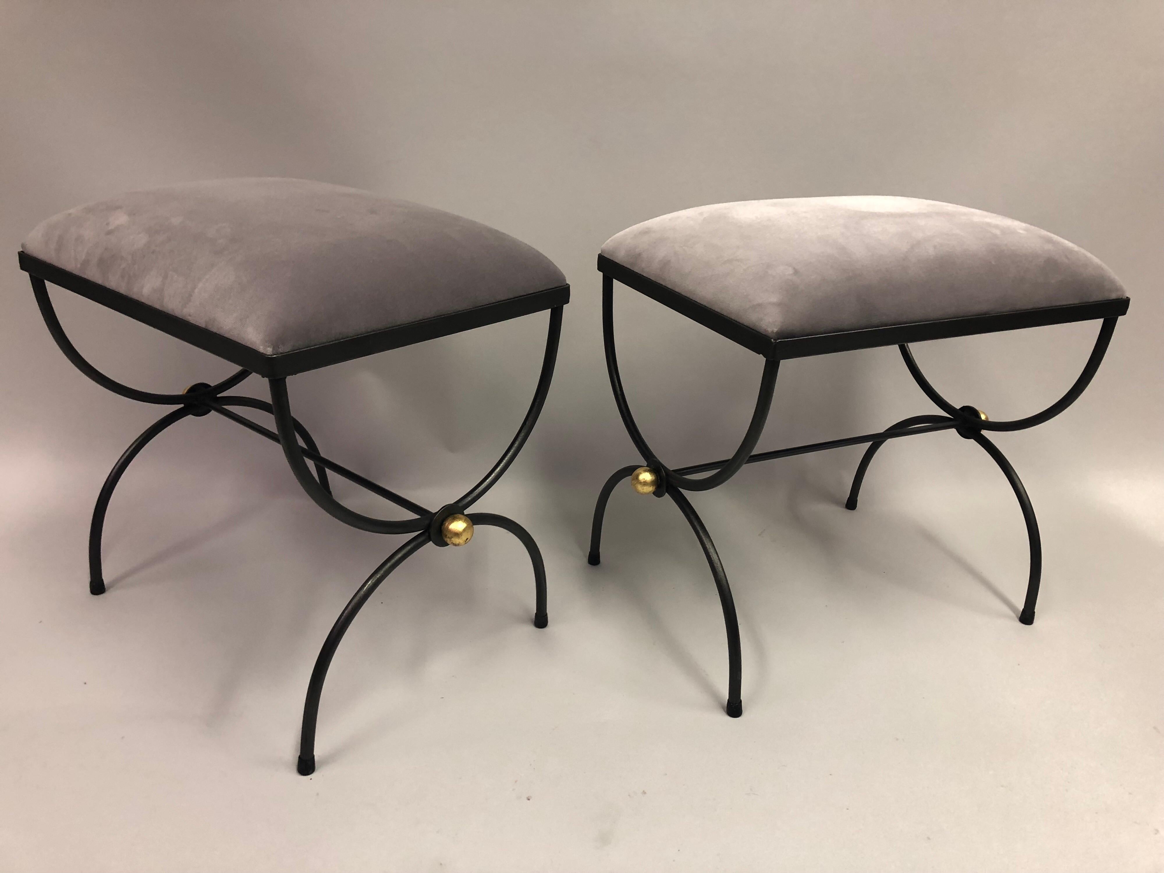 Elegant and timeless pair of French Mid-Century Modern neoclassical handwrought iron and gilt benches or stools attributed to Maison Baguès. The pieces are in a Classic Curile / X-Frame Design and finished with gilt iron ball finials at the