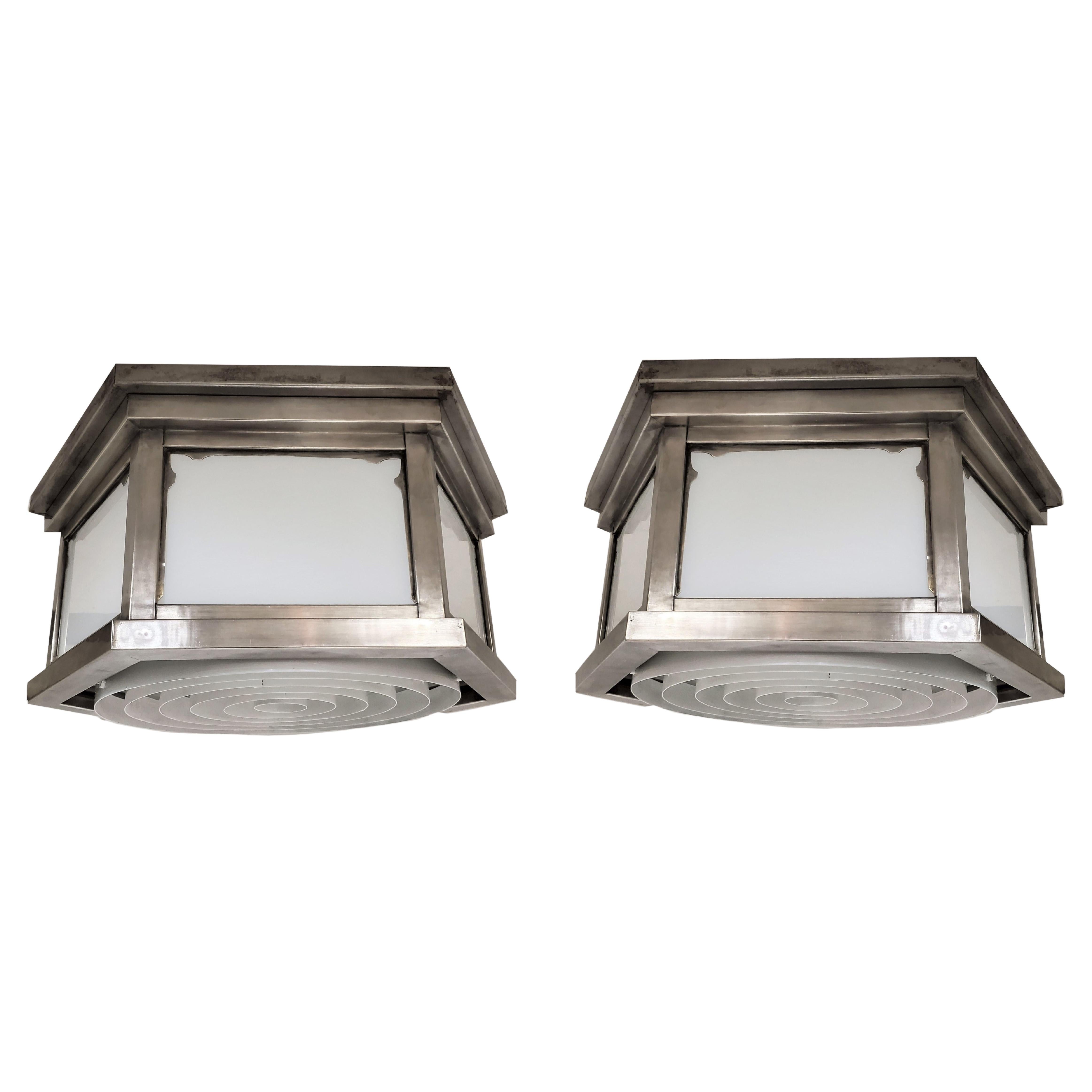 A pair of hexagonal Industrial white glass flush mounted fixtures with stepped designed frames in a warm satin nickel over brass. The six sided shape features opaque white glass panel insets and a concentric white painted, steel bottom surround.