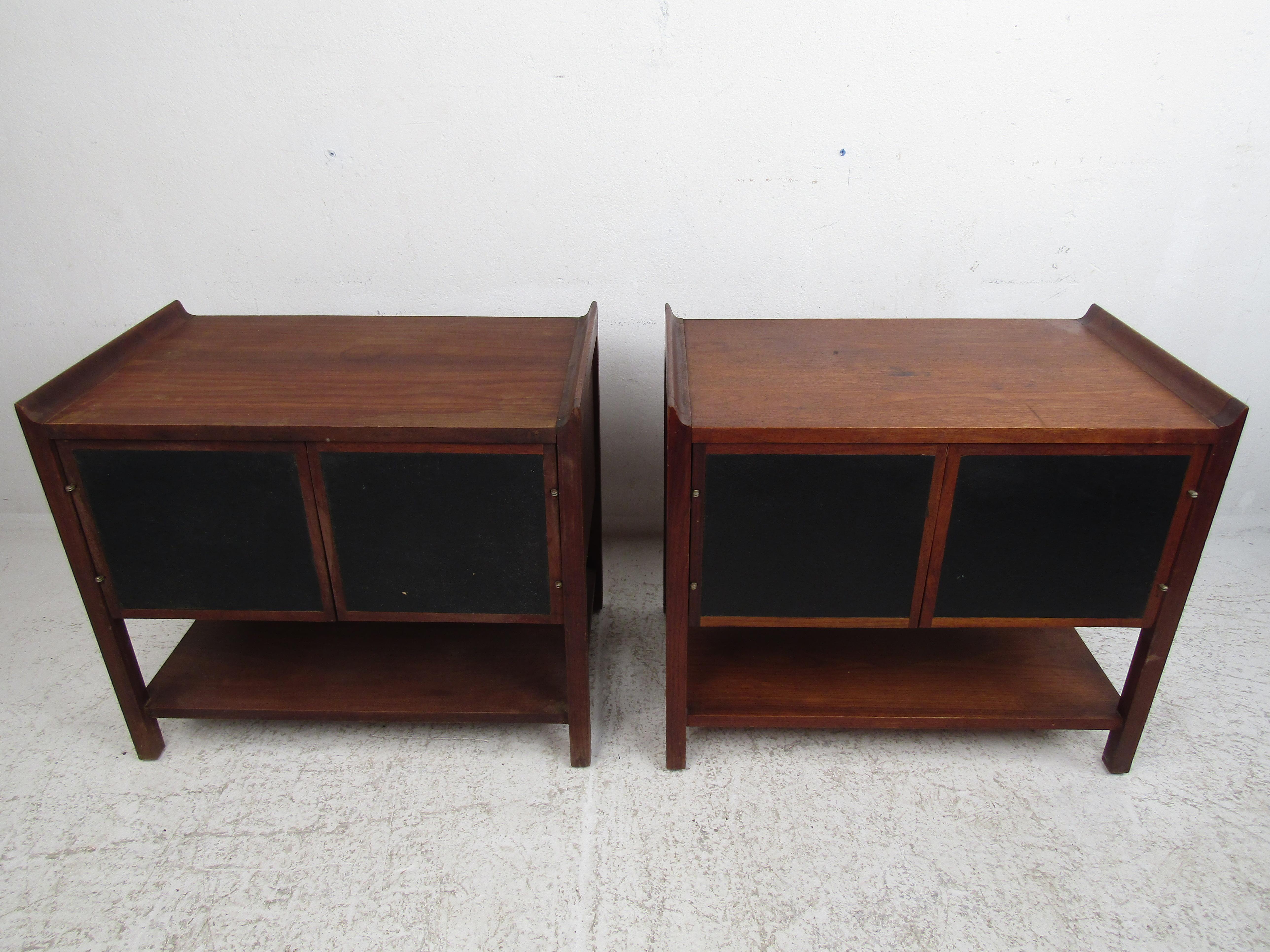 Stylish pair of Mid-Century Modern nightstands, striking design with raised edges on the tabletops, and leather-front accents on the cabinet doors. This pair is sure to make a great addition to any modern interior. Please confirm item location with