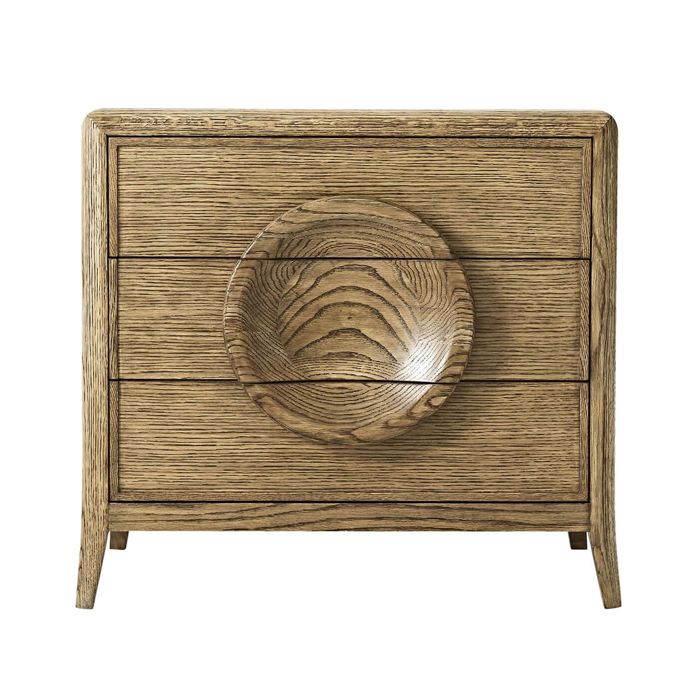 A Mid-Century Modern style solid oak and quarter oak veneered 3 - drawer nightstand. With dish form decorative drawer pulls and splayed legs. The self-closing drawers are lined on the bottoms with felt.

Dimensions: 28.5