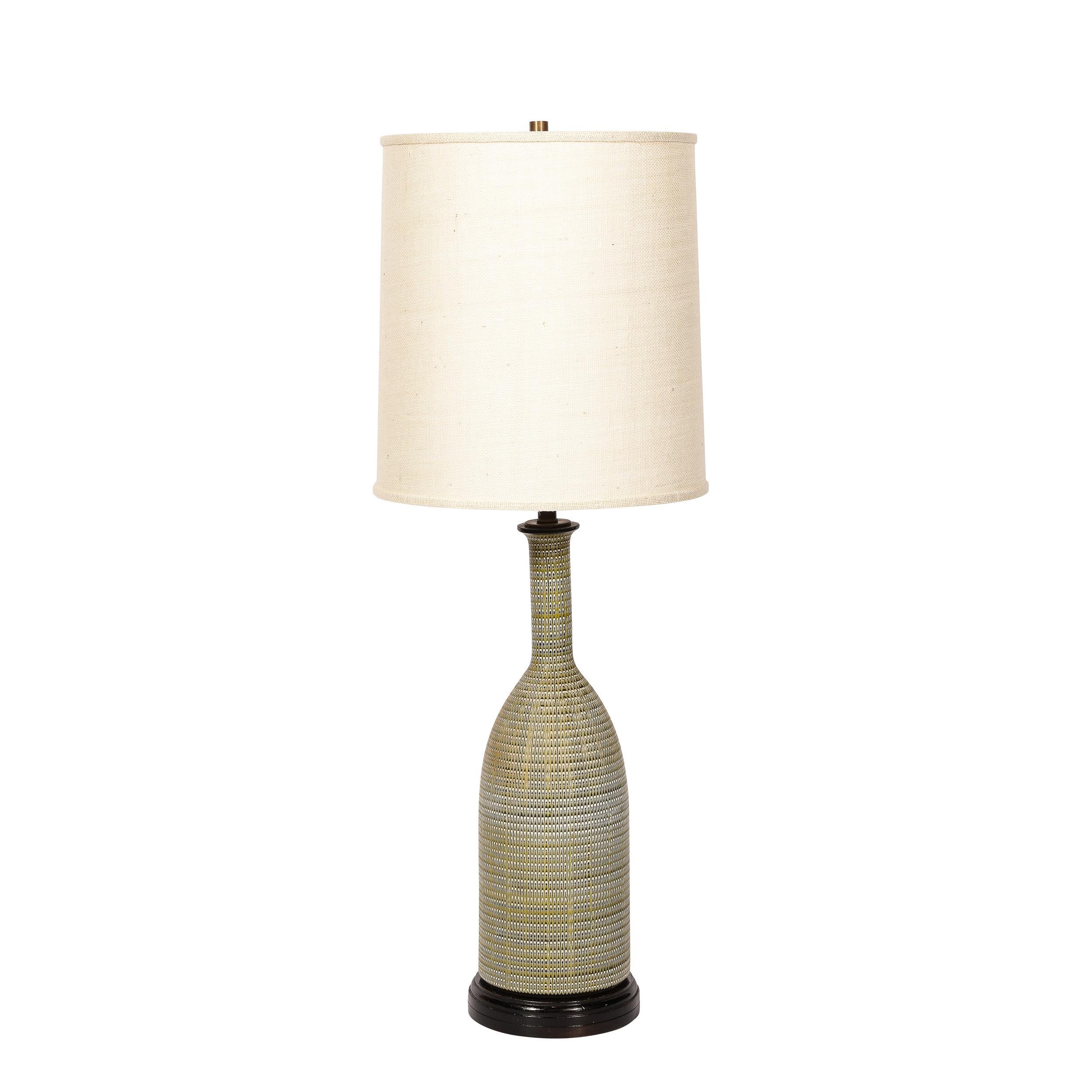 This refined pair of Mid-Century Modern table lamps were realized in the United States circa 1960. They feature conical bodies with slender elongated necks and brass fittings. The bodies of these ceramic lamps offers a sophisticated olive background