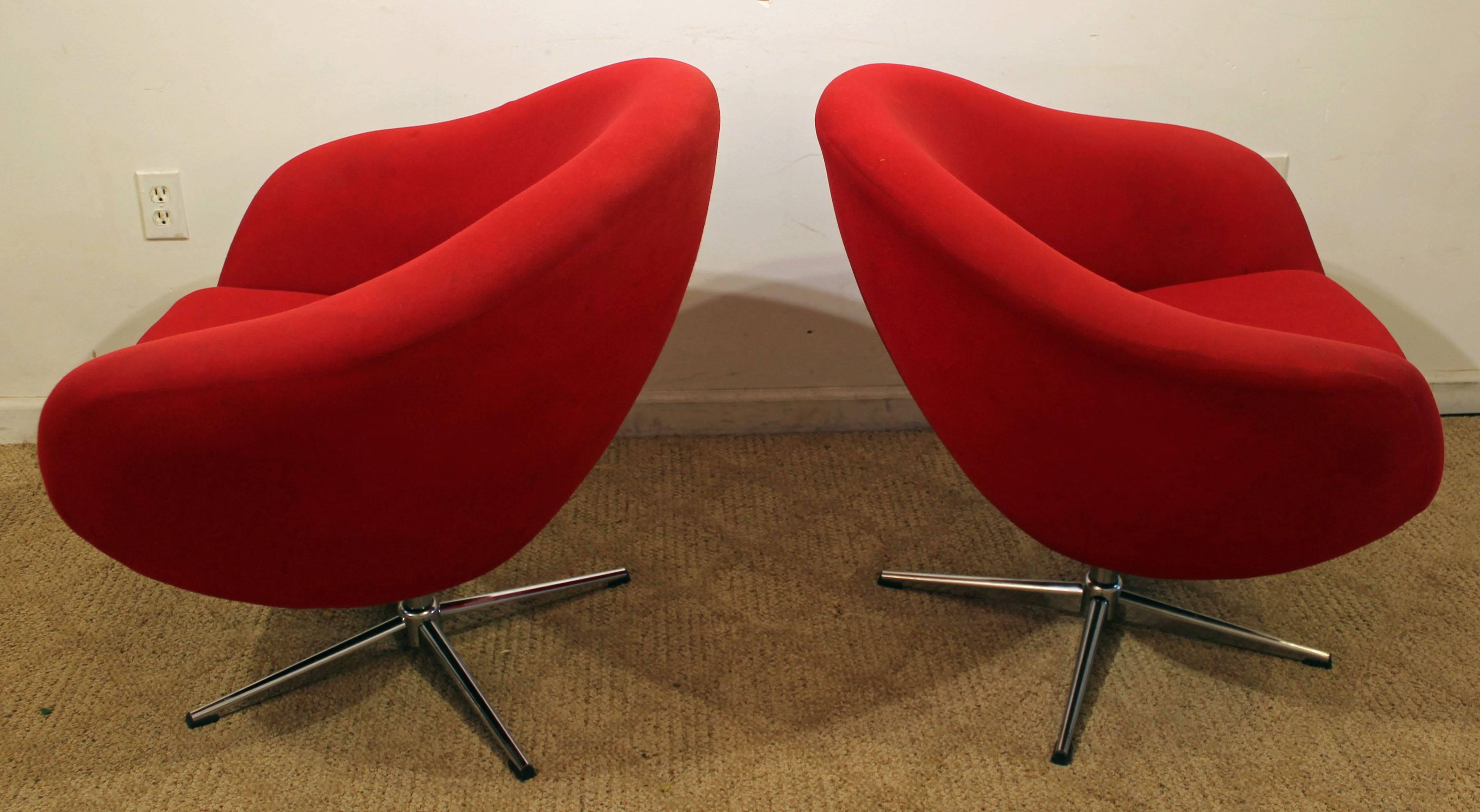 This set includes two chrome swivel pod chairs by Overman, featuring a chrome base and red upholstery. They are in decent condition, but can stand to be redone.