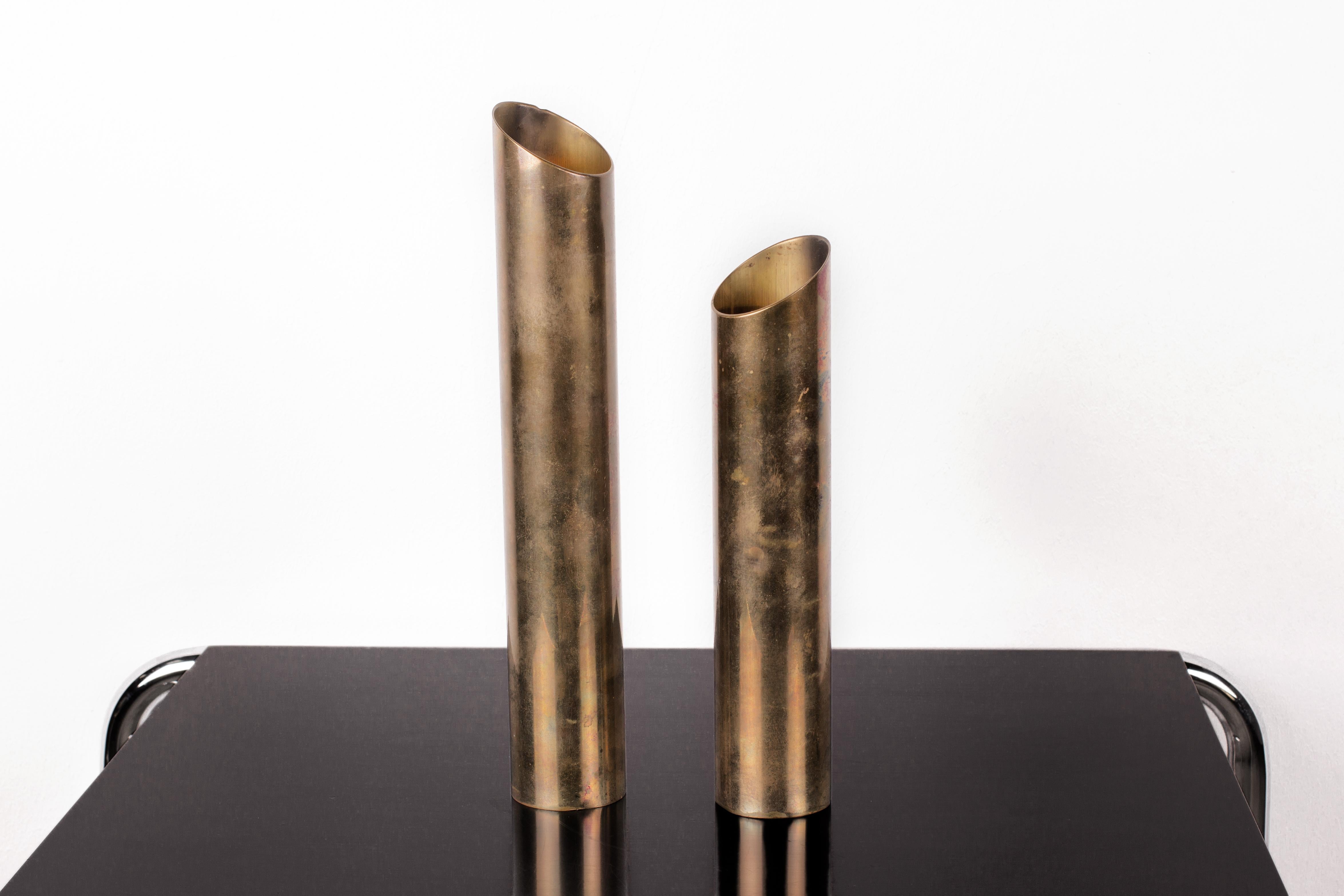 Elegant, minimalist Mid-Century Modern patinated brass candlestick holders from Scandinavia. Tubular form with 45 degree cut. Can either completely envelope a tea candle so that only the soft light bounces out off the inner brass tubing.