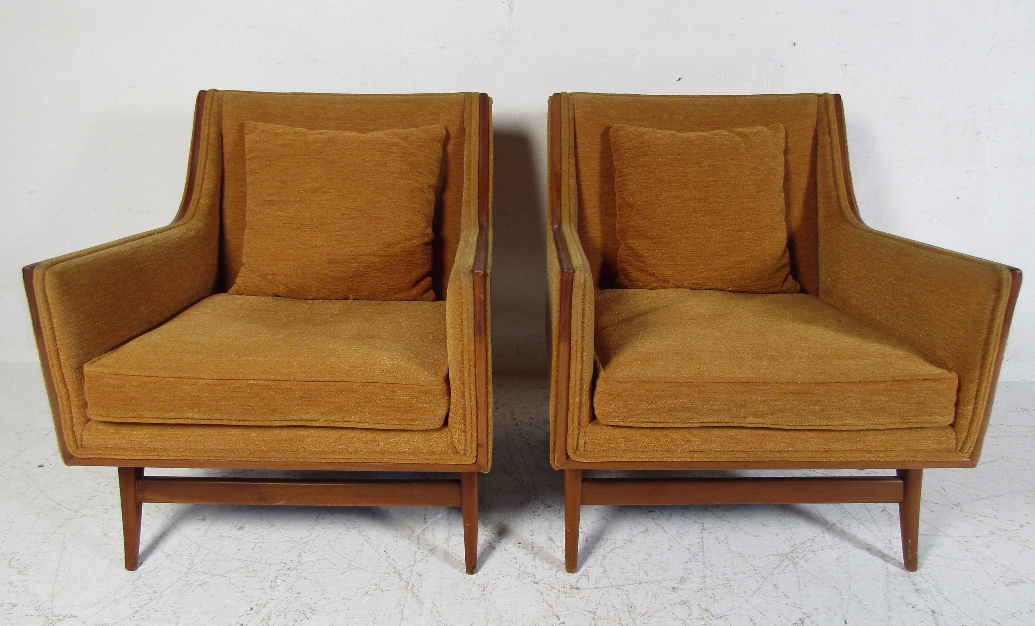 This beautiful pair of vintage modern armchairs feature plush orange colored upholstery and a sturdy walnut frame. The splayed legs and sloped armrests show quality craftsmanship. A thick padded seat cushion and backrest pillow ensure optimal