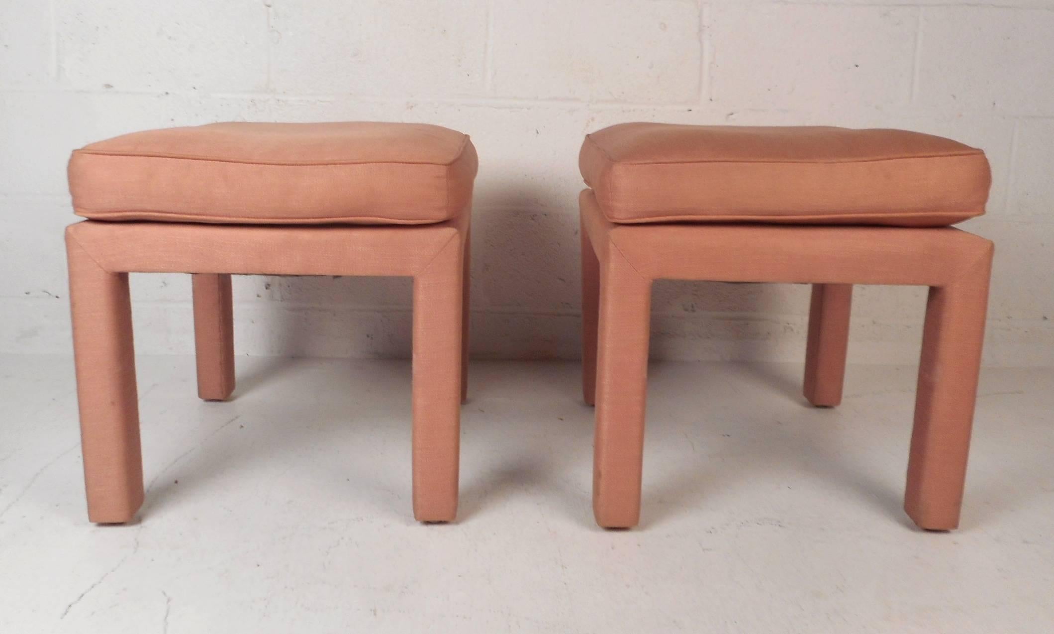 A stunning pair of vintage modern ottomans covered in soft pink upholstery. A stylish and comfortable design with a thick padded cushion on top. This wonderful midcentury pair of stools make the perfect addition to any home, business, or office.