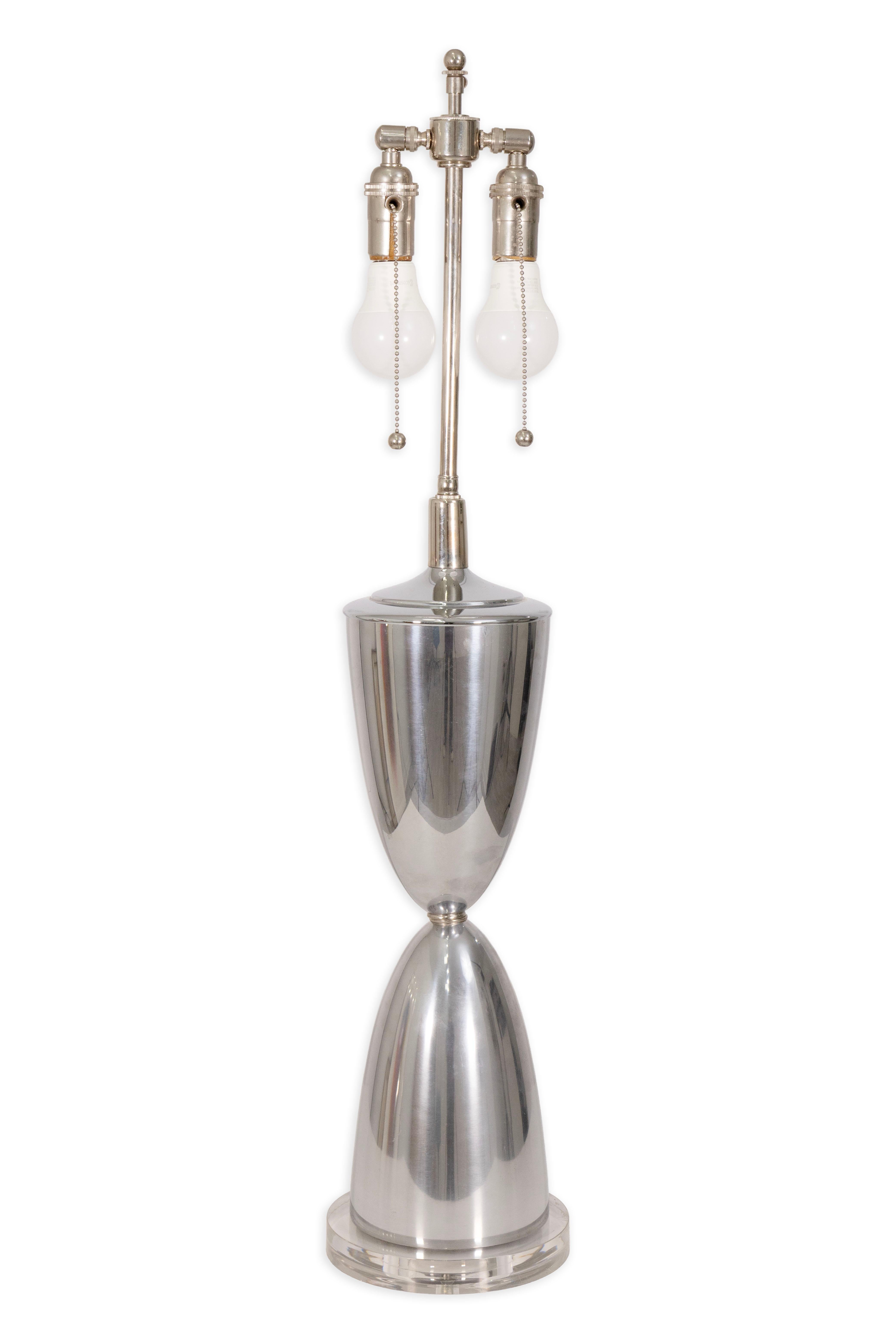 Questa raffinata coppia di lampade da tavolo del Mid Century Modern è caratterizzata da forme eleganti e scultoree realizzate in alluminio lucido, che poggiano su basi in lucite trasparente. La silhouette a doppio cono crea un sorprendente profilo a