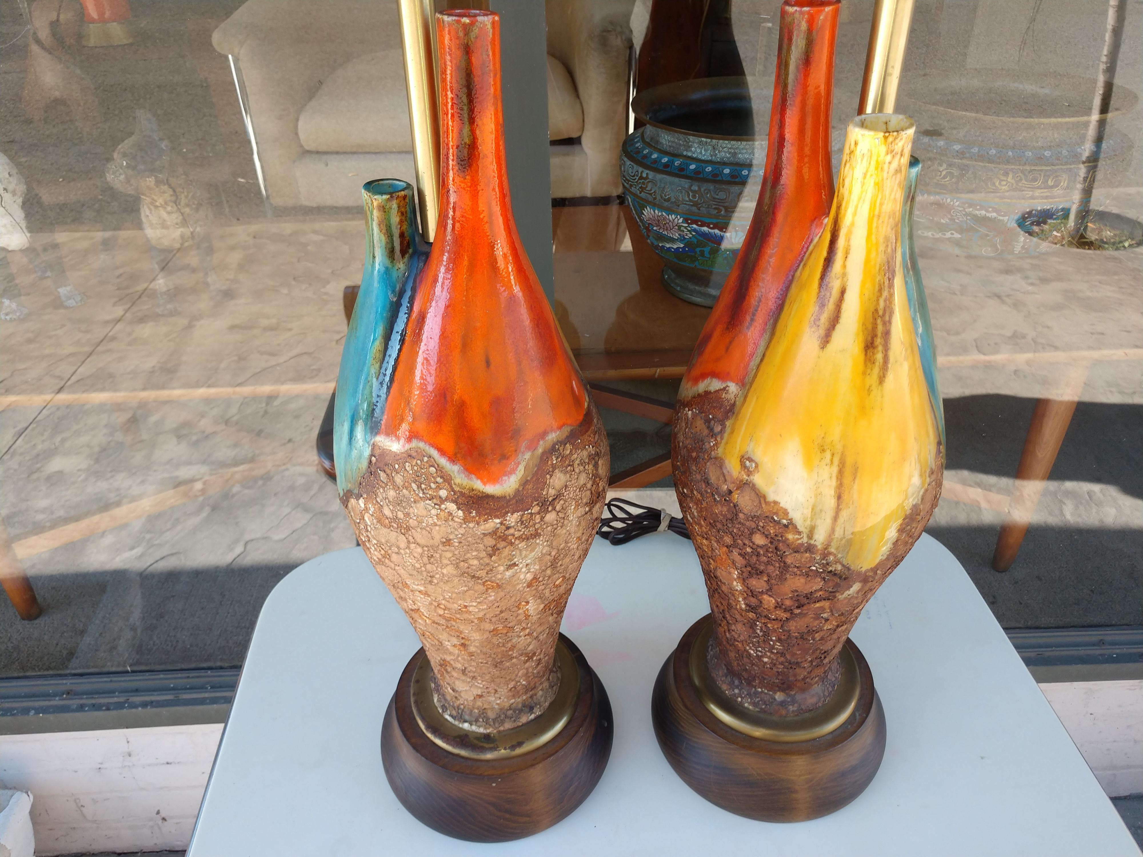 Fabulous pair of mid century lamps glazed in fantastic color with a Molton lava like lower half. Brass fittings with a walnut base. Lamps are tall 27.5 to the top of the socket with a 7.25 inch base. 37 to the top of the shades. Shades not included.