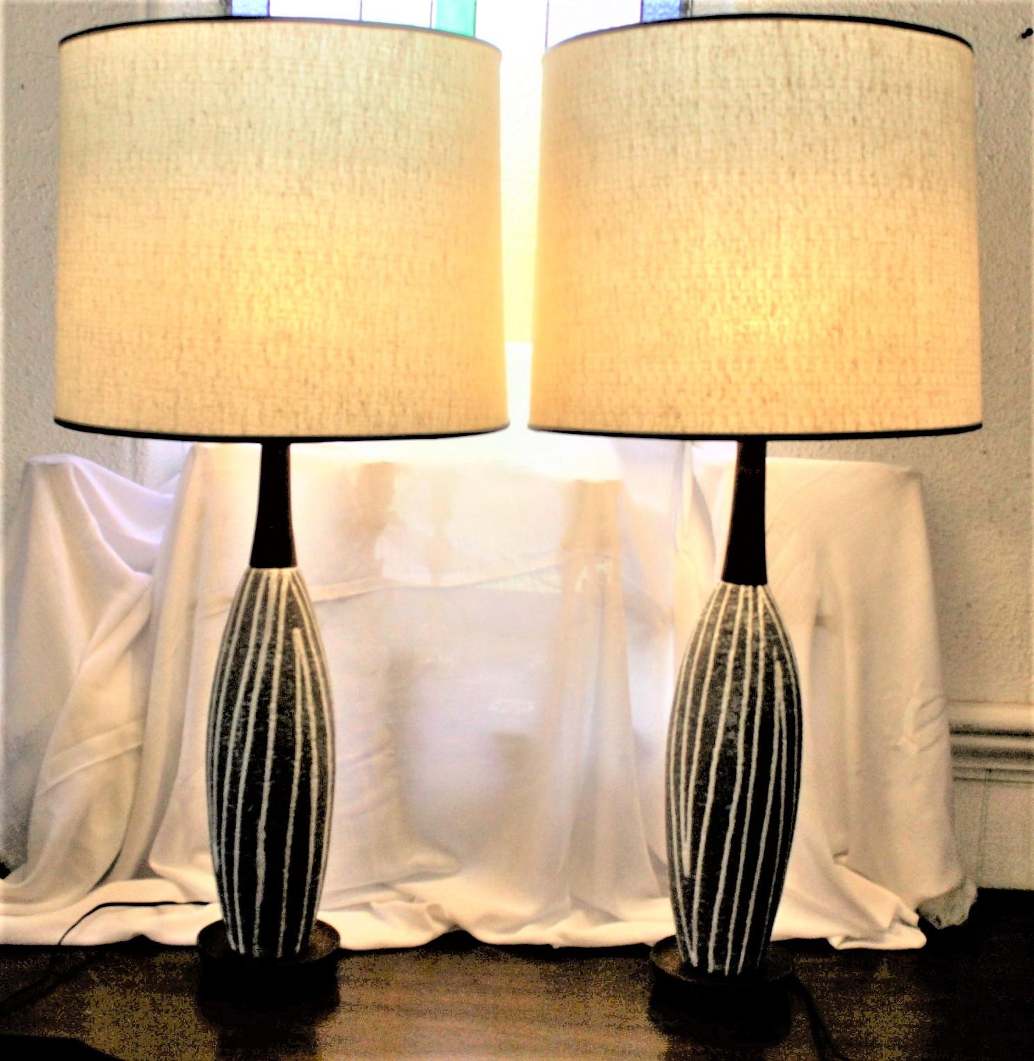 This pair of Mid-Century Modern pottery table lamps were made by the Swedish art potter Upsala Ekeby in approximately 1965. The lamps are done with a green or turquoise glaze with cream swirled lines running horizontally on the textured bodies of