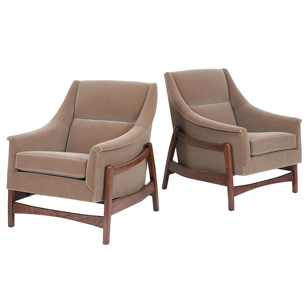 This remarkable 1960s pair of Mid-Century Modern Lounge Chairs are handcrafted out of teak wood, have a sleek design base, and the frame allows for the seat to rock with ease. These rocking chairs have been professionally reupholstered in beautiful