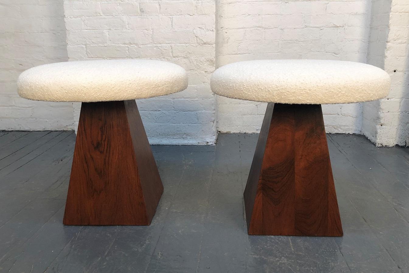 Pair of Mid-Century Modern rosewood stools. Nice rosewood grain having triangular shaped bases with round off-white bouclé fabric covered cushioned seats.