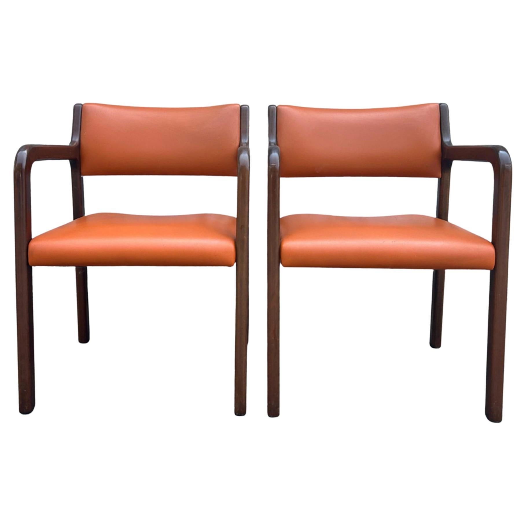 Pair of Mid-Century Modern Rounded Walnut arm chairs with Orange Upholstery. Very Nice Pair of curved rounded arm chairs. Orange Vinyl Upholstery. Very clean chairs. Made in USA Located in Brooklyn NYC.

 
