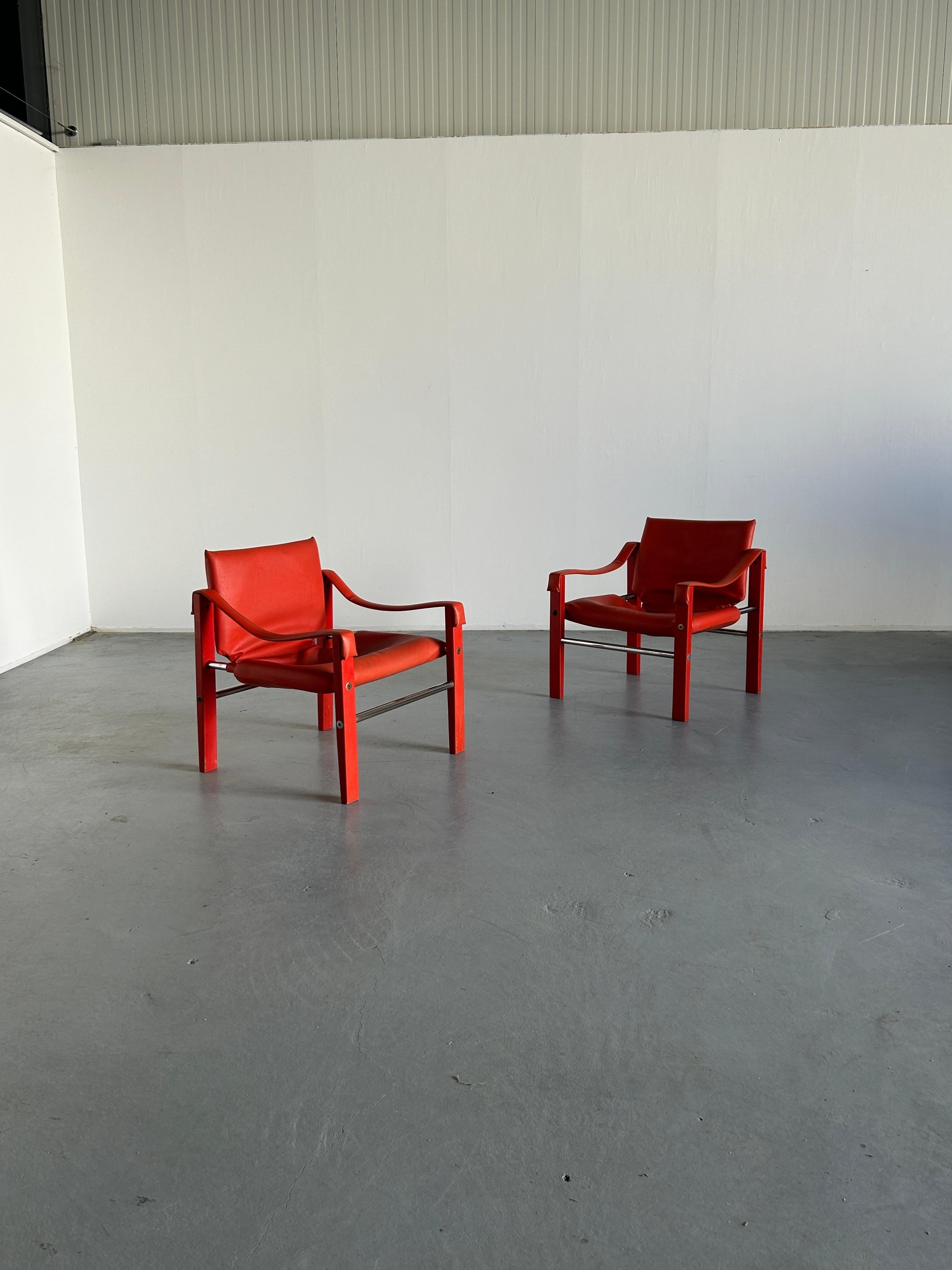 Rare edition vintage Safari chairs designed by Maurice Burke for Arkana Furniture, wearing their original red faux leather or vinyl with a coloured teak frame, tubular chrome metal runners, and steel screw details. 1960s production, both original