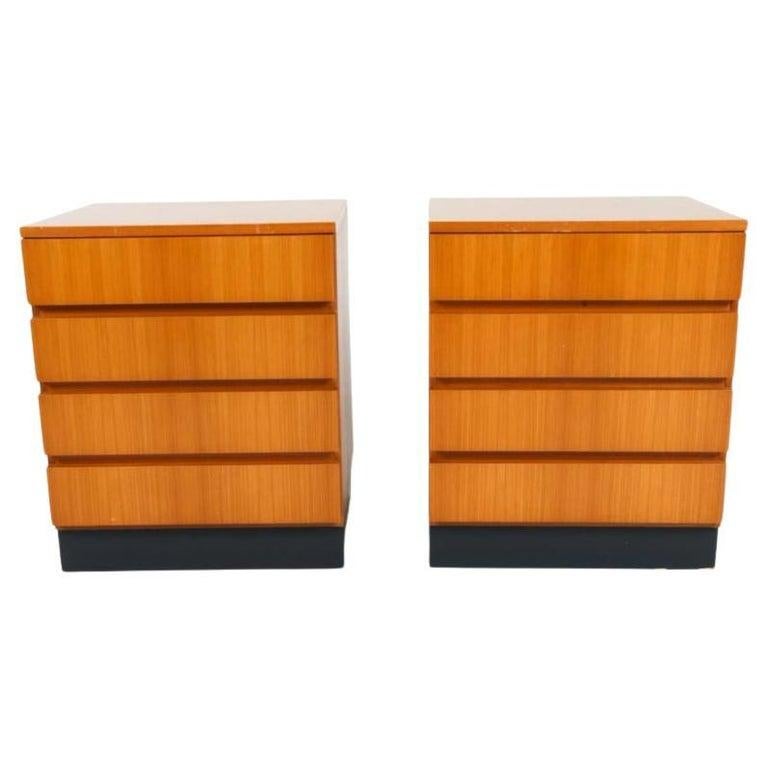 Paire de tables de nuit à 4 tiroirs en hêtre blond de style scandinave moderne du milieu du siècle dernier sur un socle en laque noire. Magnifique placage de hêtre au grain clair et au design géométrique symétrique. Chaque table de nuit comporte 4