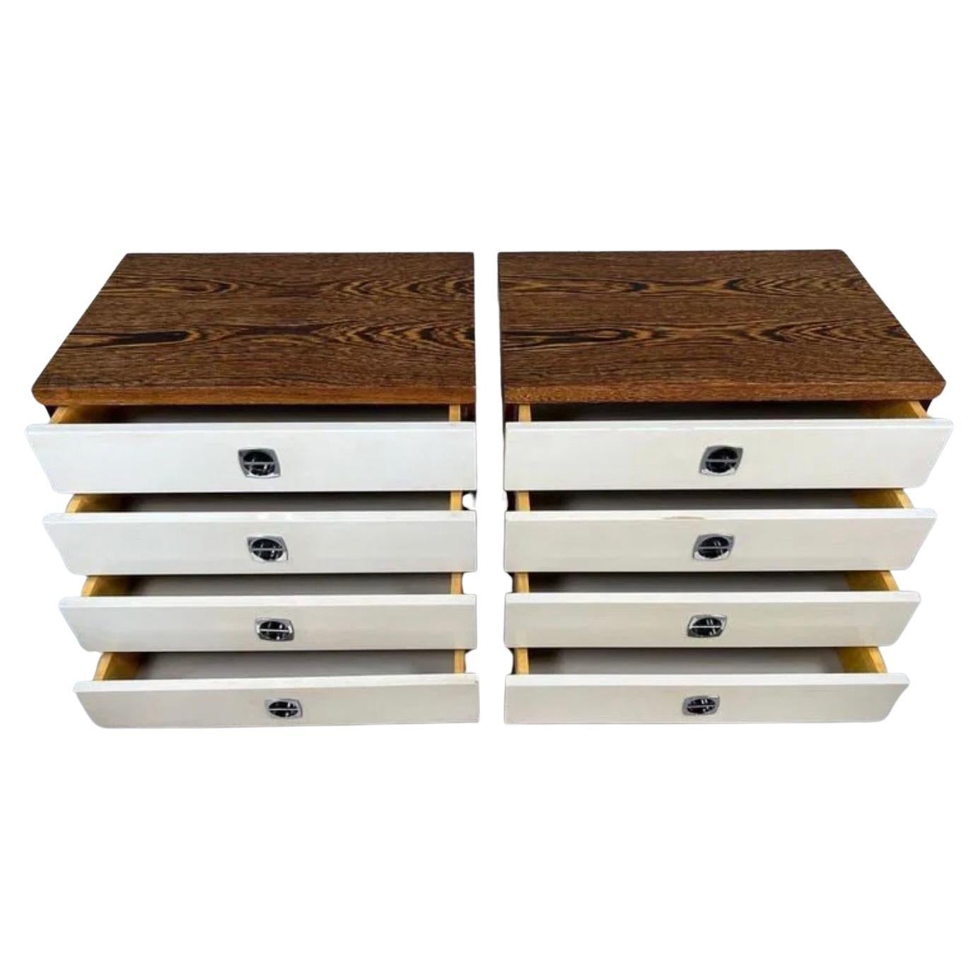 Pair of Mid century modern Scandinavian 4 drawer nightstands with White lacquer drawers on a plinth base. Beautiful grained wood veneer with geometric symmetrical design each nightstand having 4 drawers with chrome handles. Clean all around ready
