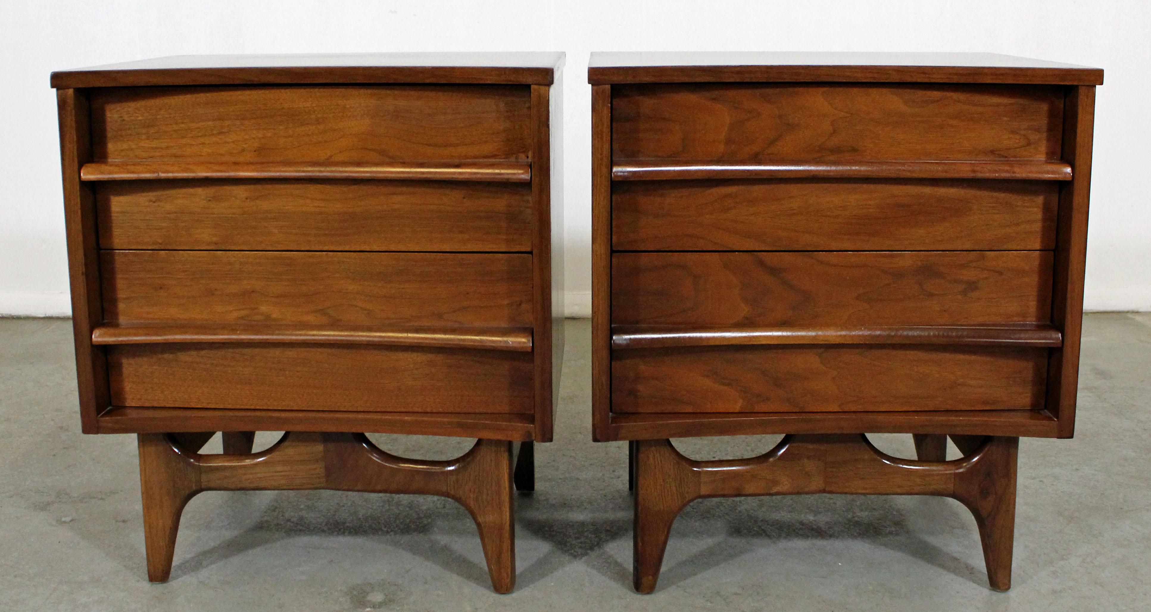 Offered is an excellent example of American Mid-Century Modern design. Includes a pair of walnut nightstands with two dovetailed drawers (each) and sculpted pulls. They have been refinished and are in good condition, showing some surface wear. They
