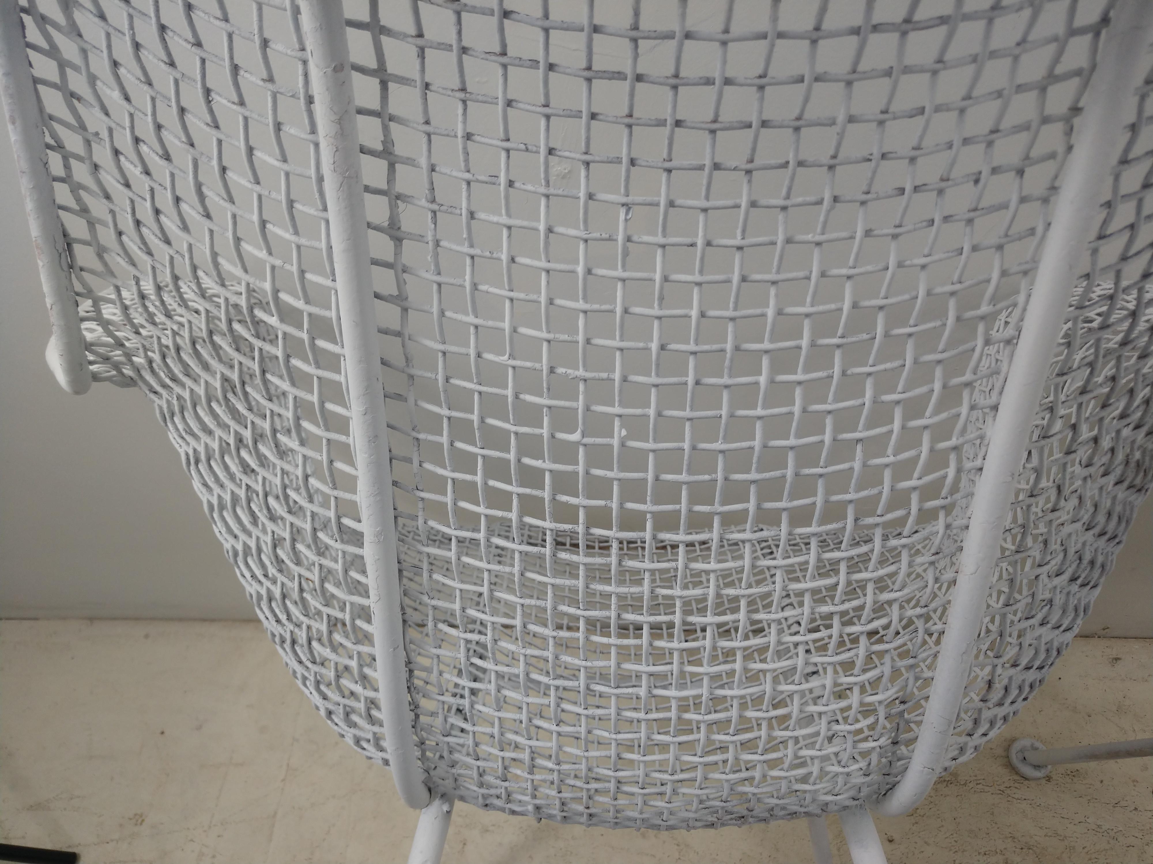 Pair of iconic outdoor armchairs by Russell Woodard, sculptural. Created and designed in the 1950s these chairs have remained in vogue for over half a century. Chairs were recently sprayed white. Seat height is 16.5. Molded wire mesh in a tight