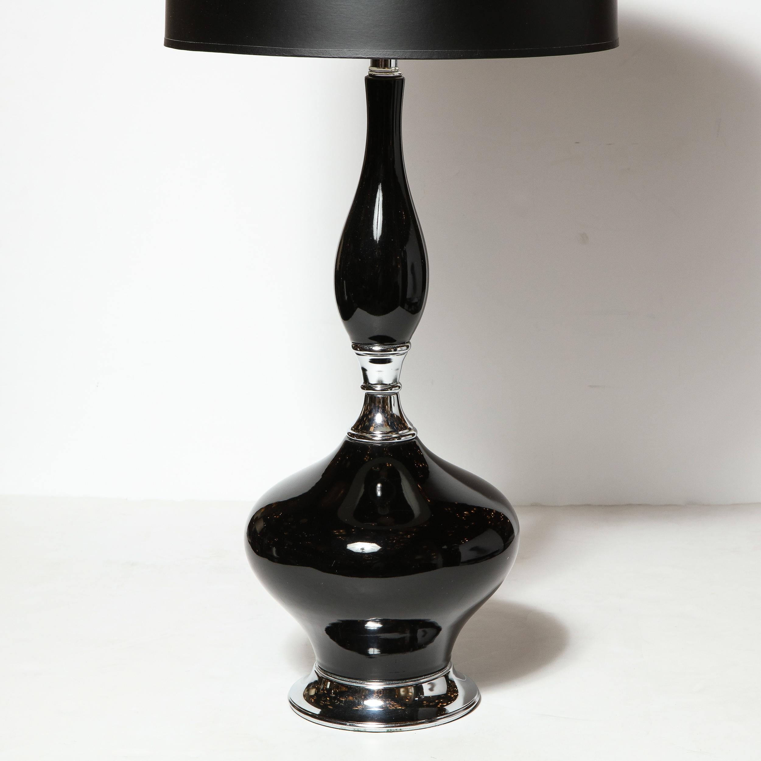 This beautiful pair of Mid-Century Modern ceramic lamps were realized in the United States, circa 1960. They feature an organic protuberant form- full of sinuous curves- finished in a lustrous black glaze that extends upwards from a lustrous chrome