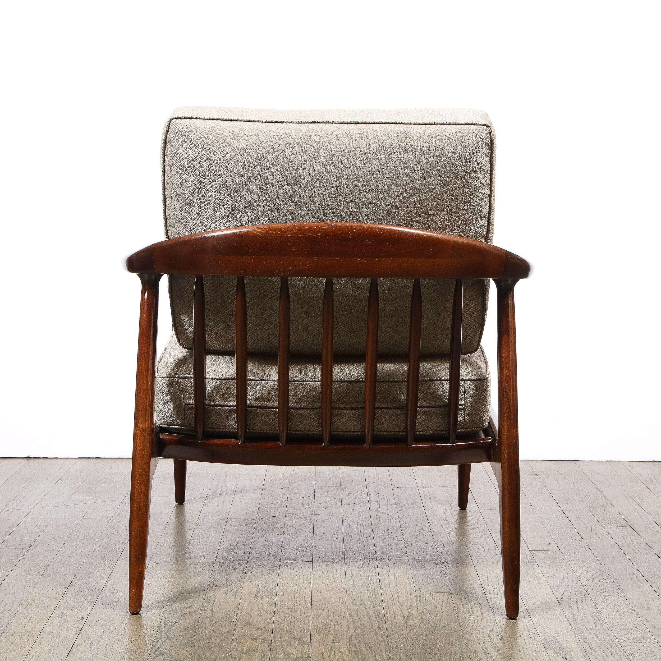 This sculptural and elegant pair of Mid Century Modern arm chairs were realized in the United States circa 1950. They feature elegantly contoured walnut arms and feet full of oblique angles and idiosyncratic symmetries. Additionally, the back offers