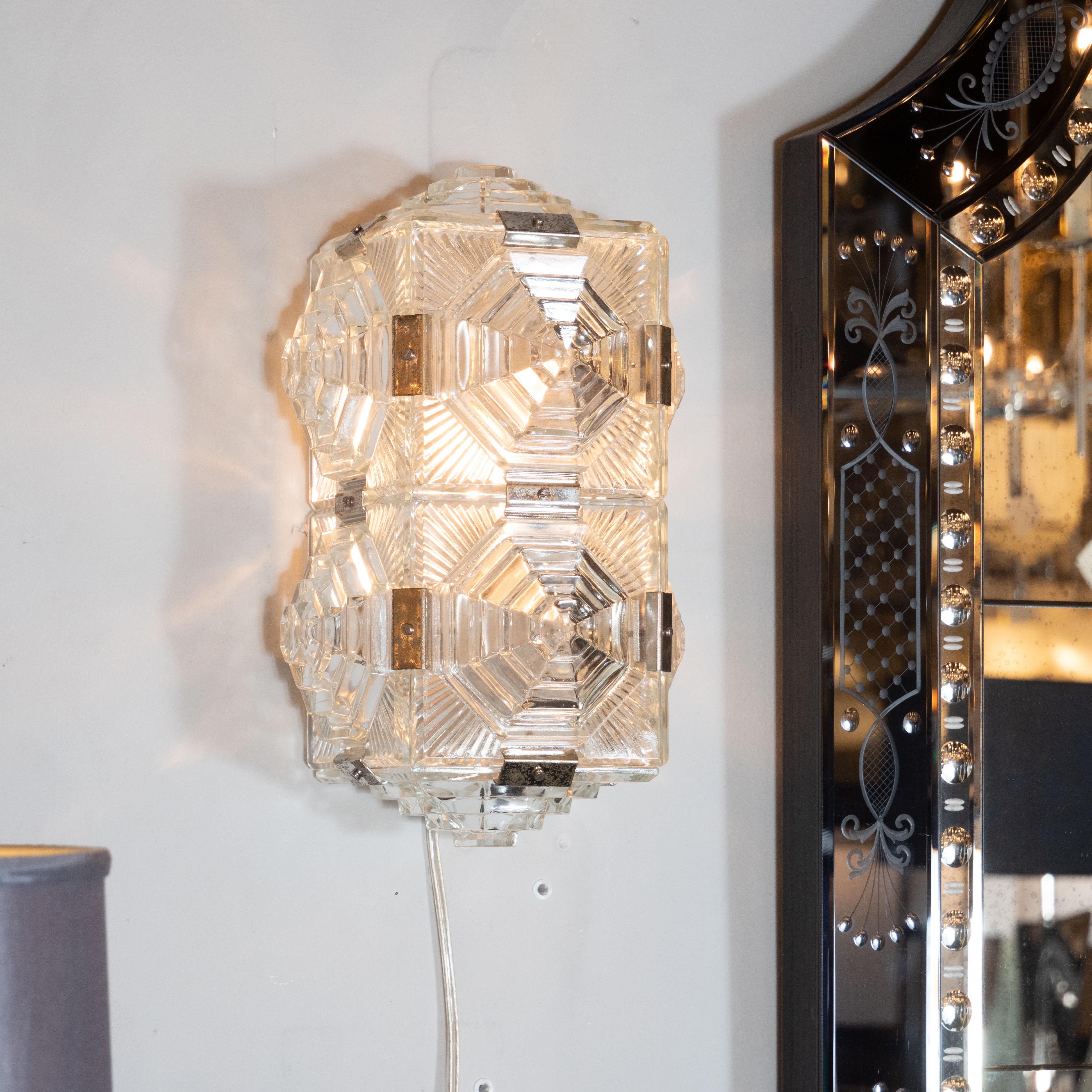 This stunning and graphic pair of Mid Century Modern sconces were realized by Kinkeldey of Austria- one of Europe's finest lighting ateliers of the 20th century- circa 1960. They features eight panels of hand pressed glass- secured by chrome