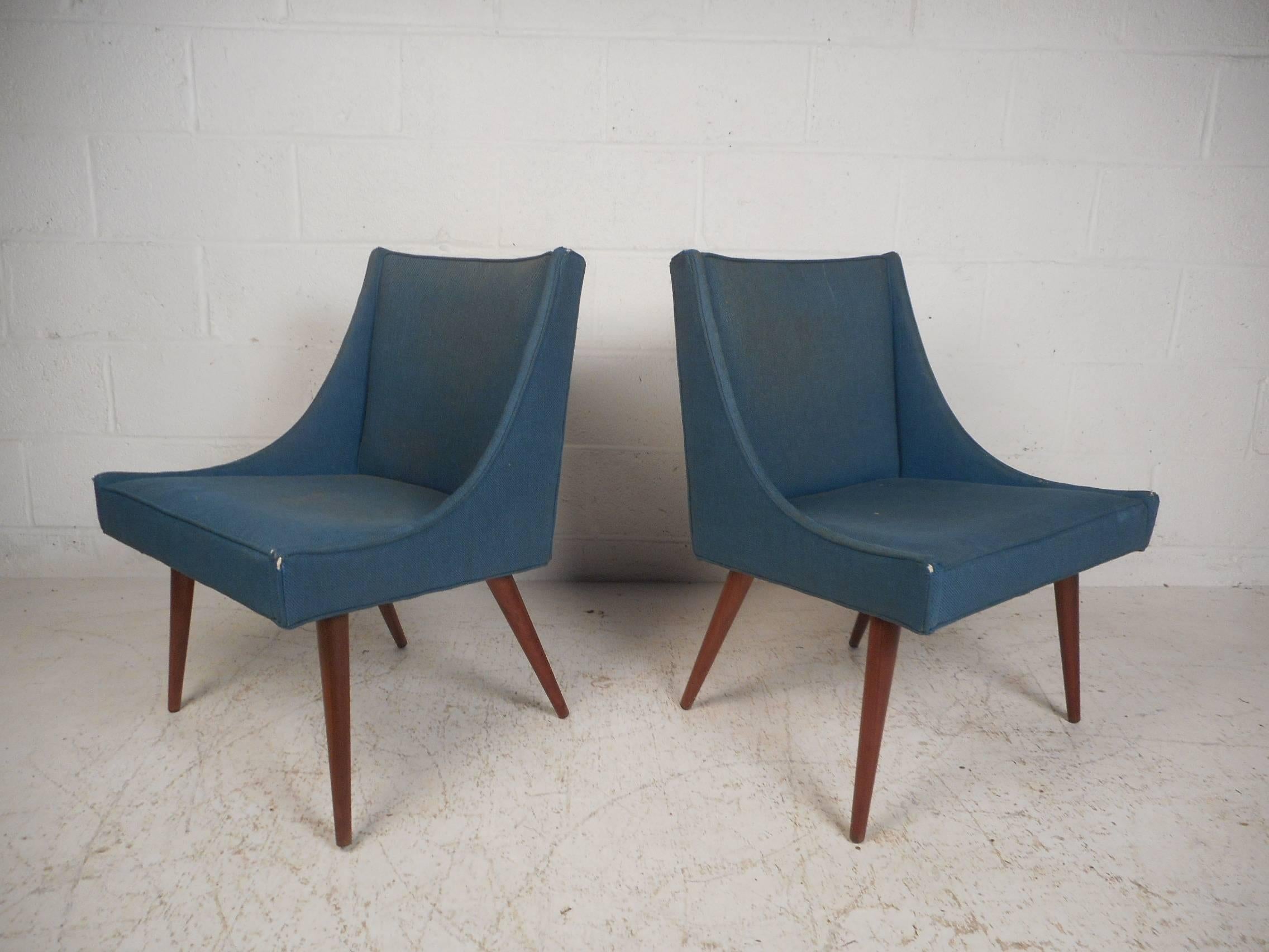 This gorgeous pair of vintage modern lounge chairs feature splayed walnut legs. A slipper style design covered in a vintage blue fabric ensures plenty of comfort without sacrificing style. This unique pair of chairs make the perfect addition to any