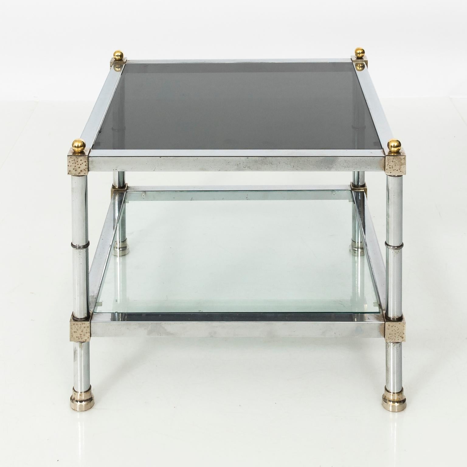 Pair of late Mid-Century Modern square tables attributed to Jansen. Two-tier, chrome frame with brass ball finials and smokey glass inserts.
 