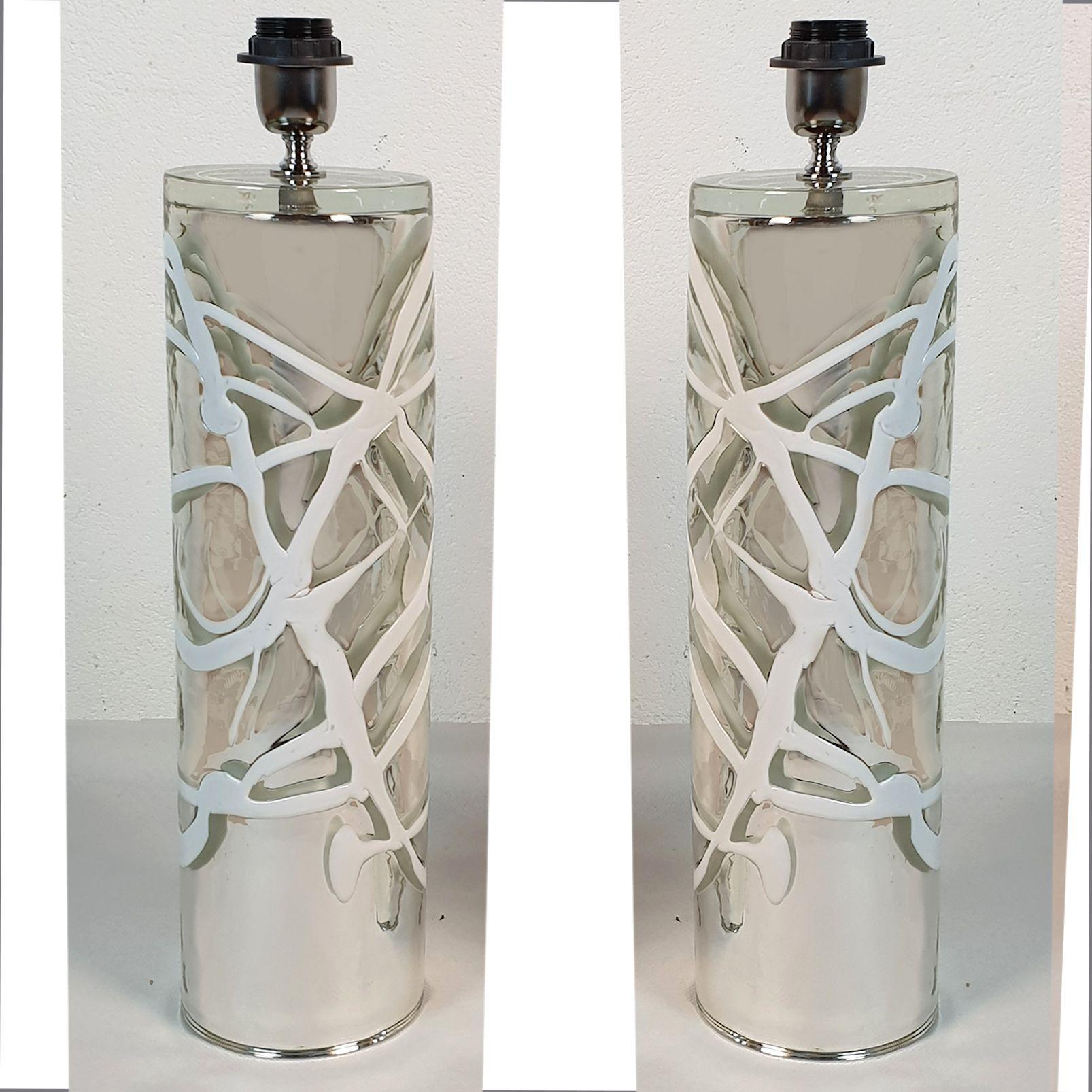 Tall pair of Mid-Century Modern Murano glass table lamps, in the manner of Venini, Italy 1970s.
The pair of table lamps have a cylindrical shape and are made of a heavy plain Murano glass.
The glass is silver and mirrored, with white handmade lines