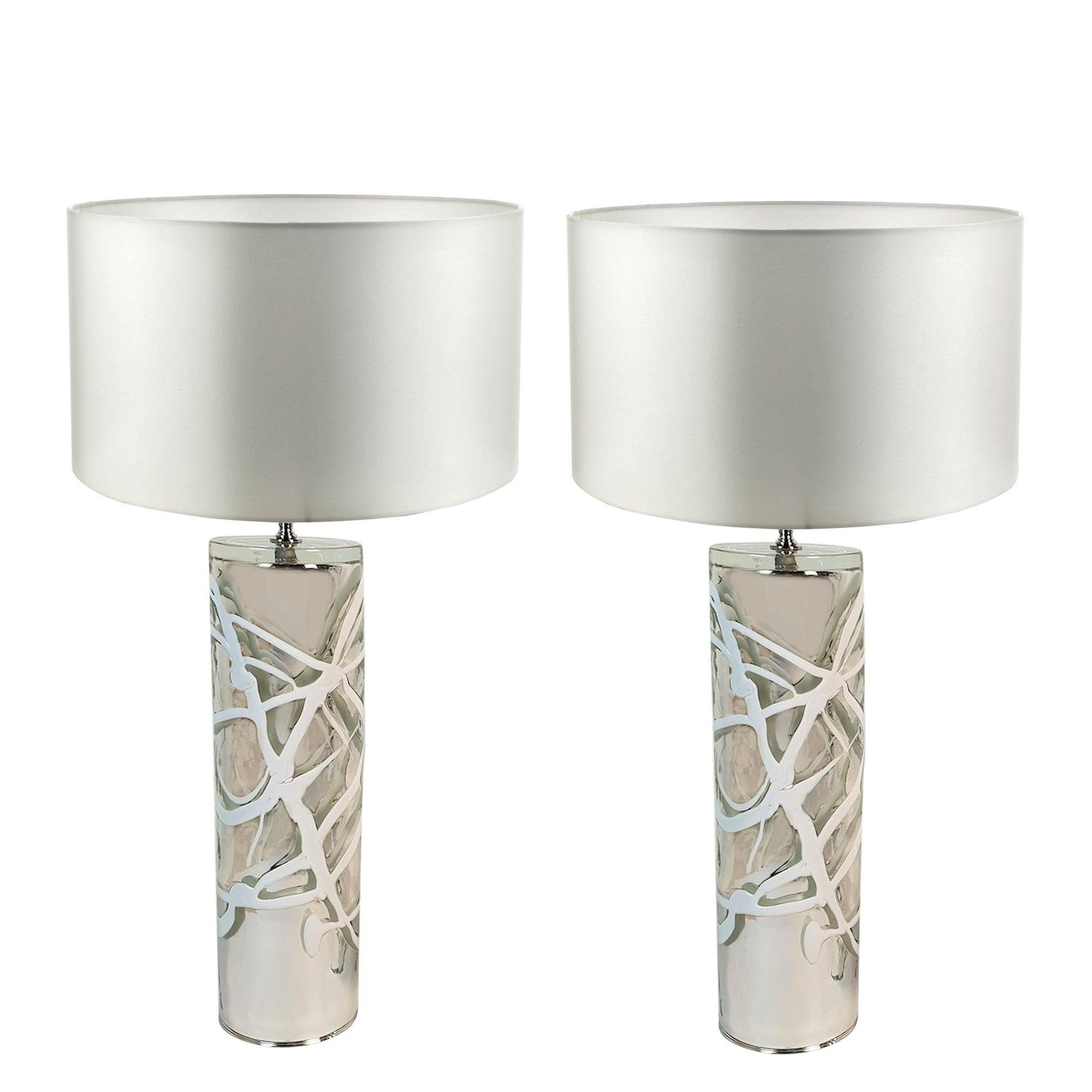 Tall pair of Mid-Century Modern Murano glass table lamps, in the manner of Venini, Italy 1970s.
The pair of table lamps have a cylindrical shape and are made of a heavy plain Murano glass.
The glass is silver and mirrored, with white handmade lines