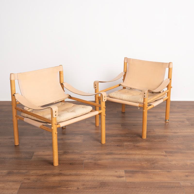 A pair of Sirocco chairs originally designed by Arne Norell in 1964 and produced by Aenby Møbler . These chairs feature the original handstitched slings, back rest and seat in a very light tan vintage leather. The chairs have original removable seat
