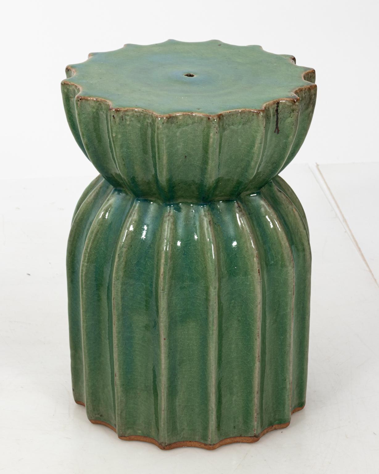 Contemporary pair of Mid-Century Modern style fluted terracotta garden stools in a soft green paint with glazed finish. Made in Asia. Please note of wear consistent with age including minor finish and paint loss along with minor crazing.