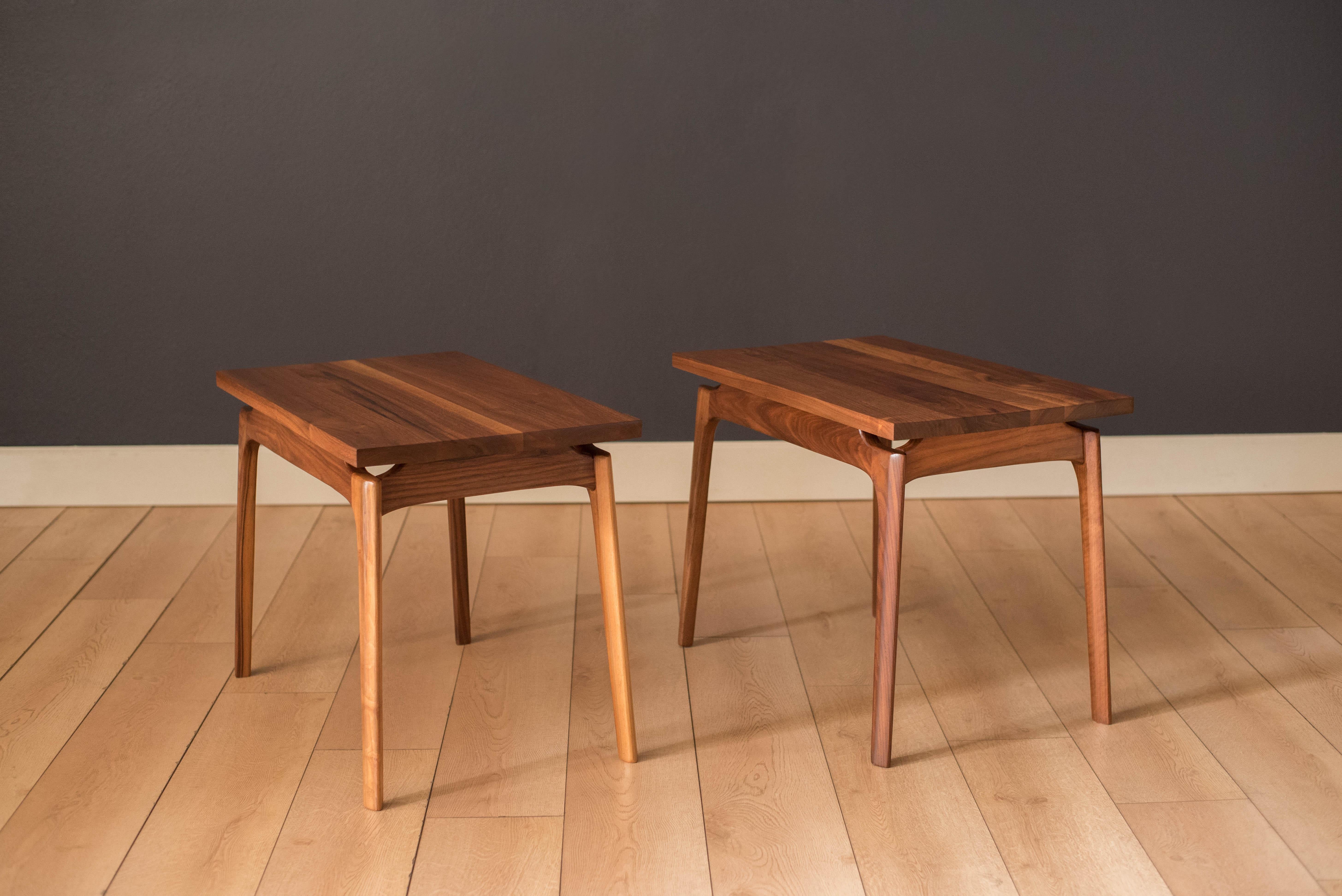 Vintage pair of side tables in solid planked walnut, circa 1960s. Features a floating tabletop design supported by contoured sculpted legs. Price is for the pair.