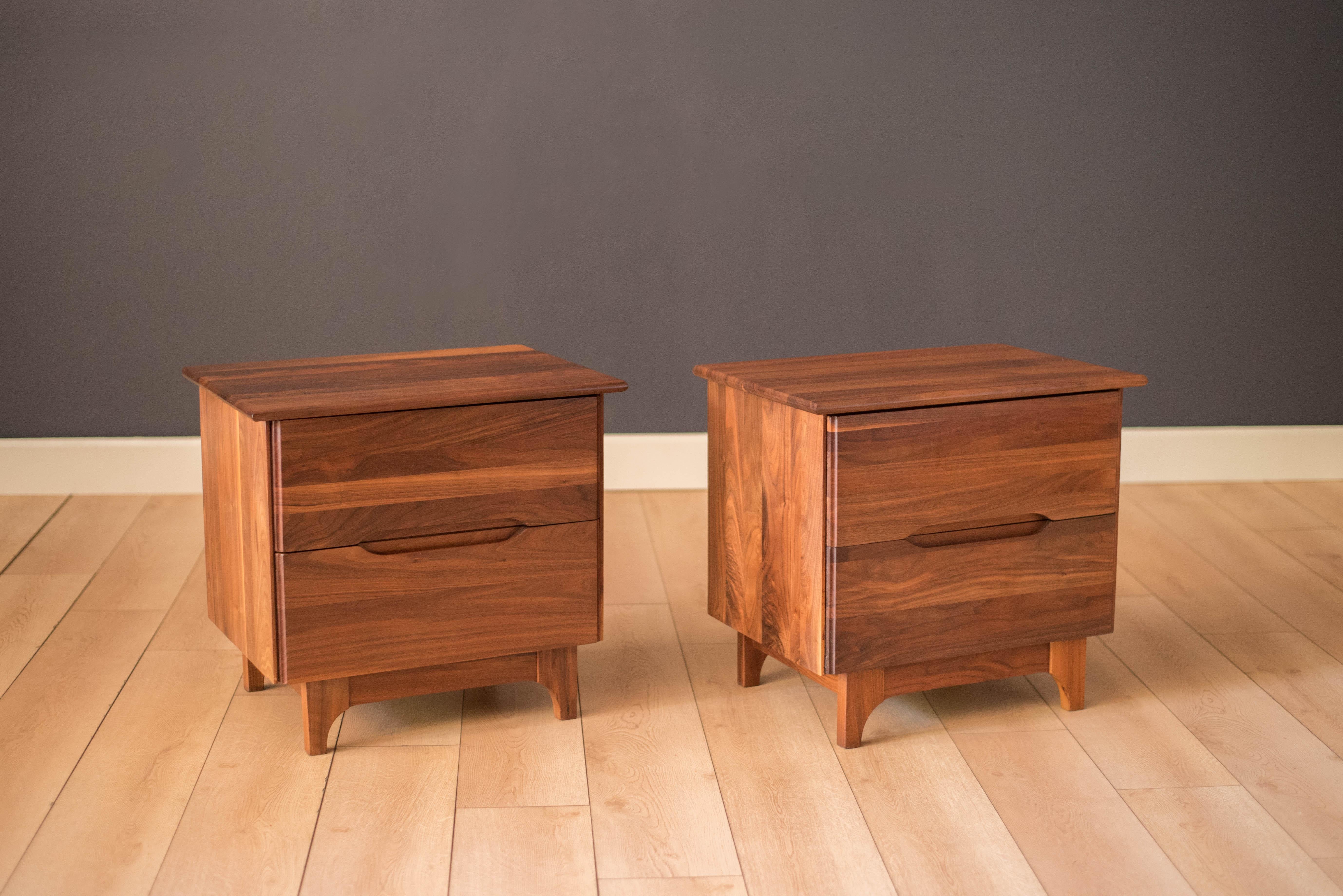 Vintage pair of nightstands in solid planked walnut, circa 1960s. This set features a stunning blend of walnut grains and includes two deep storage drawers with inset pulls. Price is for the pair. 
 